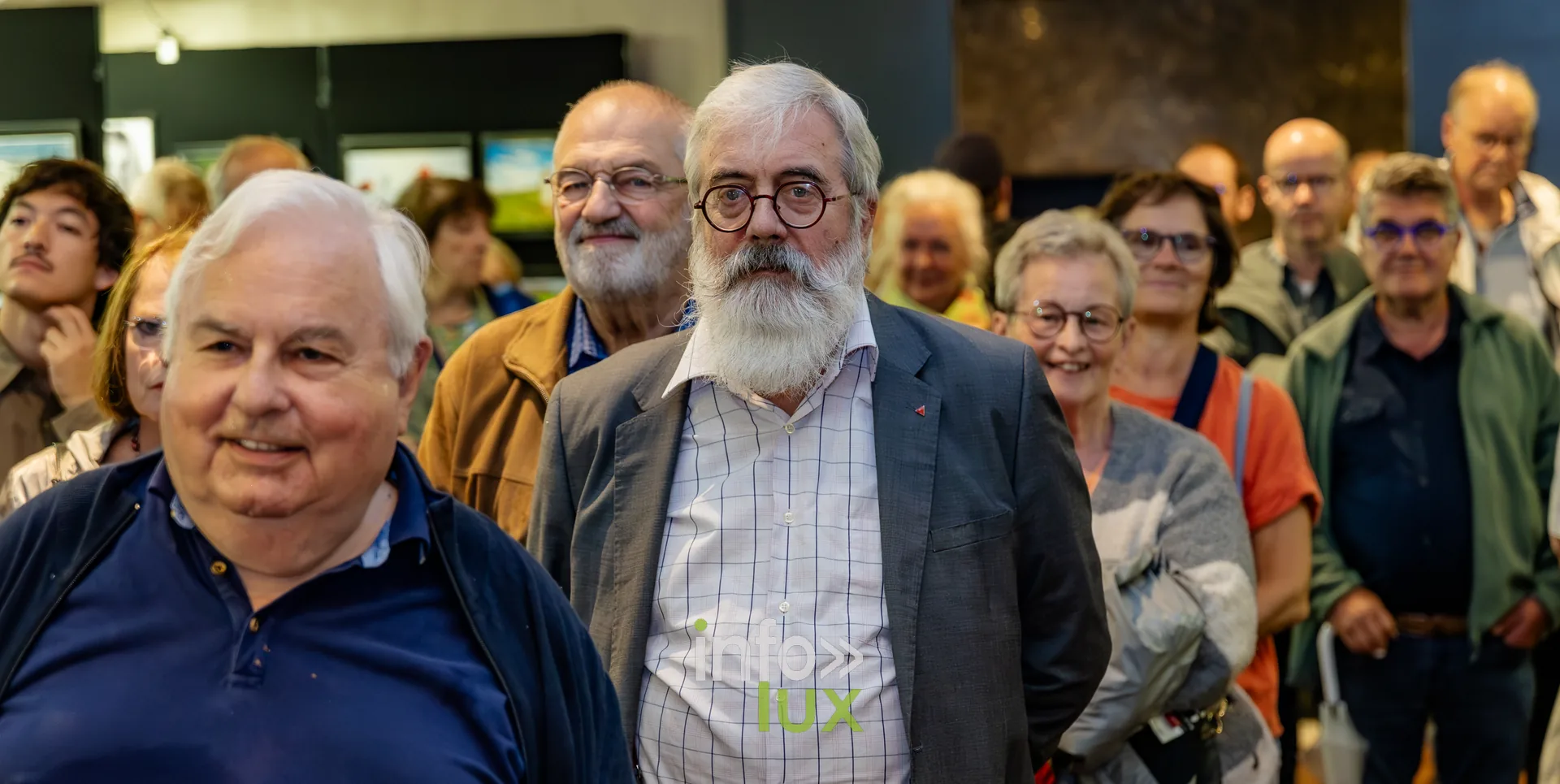 Visiteurs debout au milieu des photographies exposées lors du vernissage du Royal Photo Club Entre Nous à Nivelles