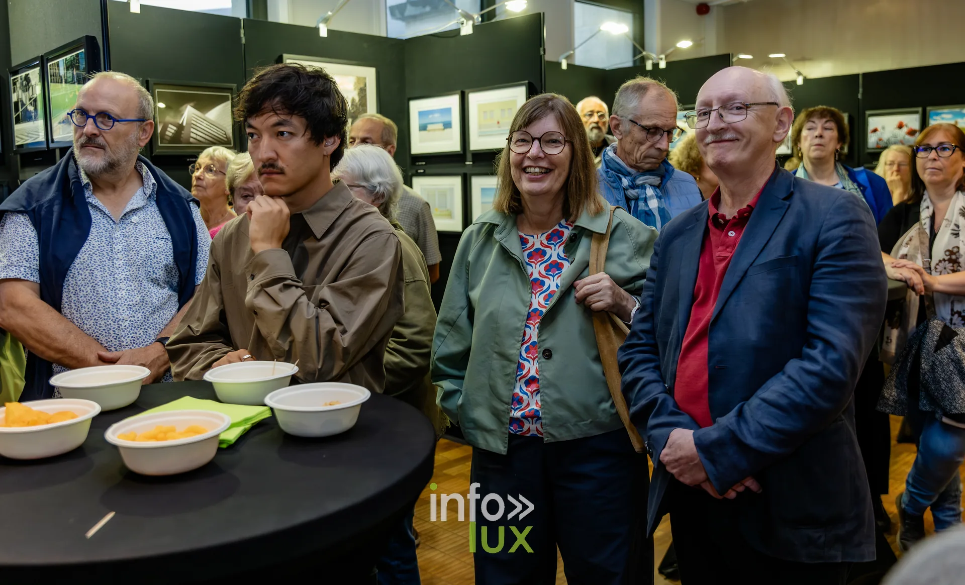 Visiteurs près des tables du verre de l’amitié lors du vernissage du Royal Photo Club Entre Nous