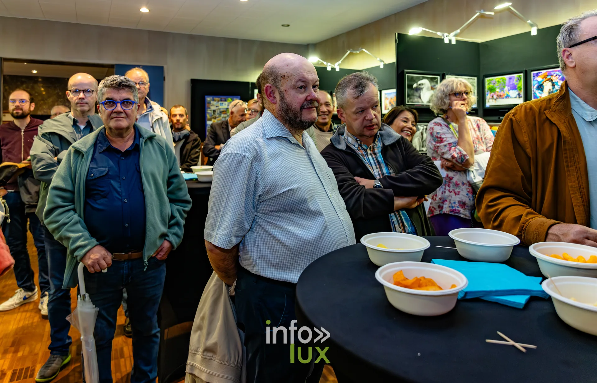 Invités debout autour des tables lors du vernissage du Royal Photo Club Entre Nous à Nivelles