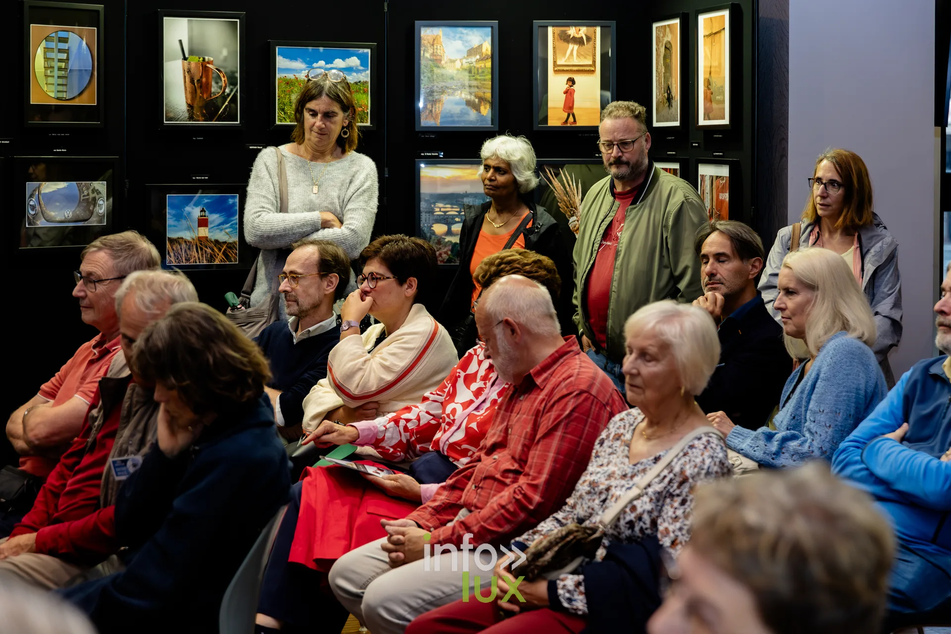 Visiteurs assis devant les cimaises de l’exposition du Royal Photo Club Entre Nous à Nivelles