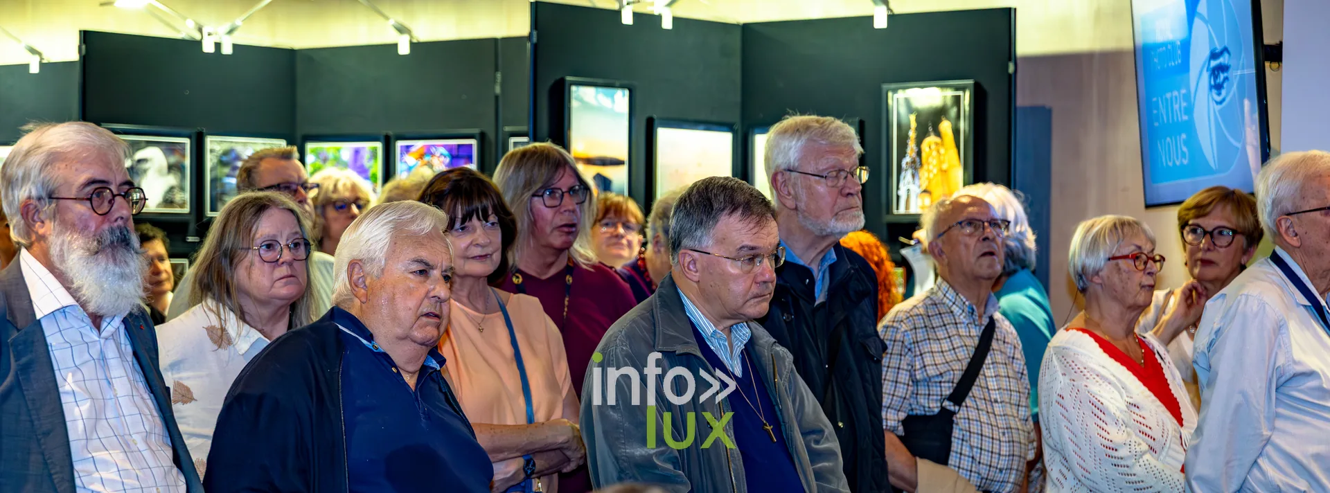 Visiteurs debout au milieu des photographies exposées lors du vernissage du Royal Photo Club Entre Nous à Nivelles