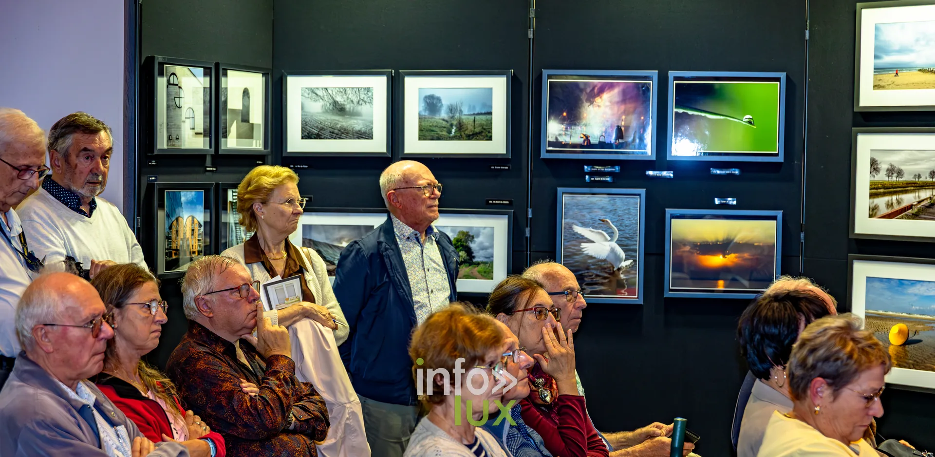 Visiteurs debout au milieu des photographies exposées lors du vernissage du Royal Photo Club Entre Nous à Nivelles