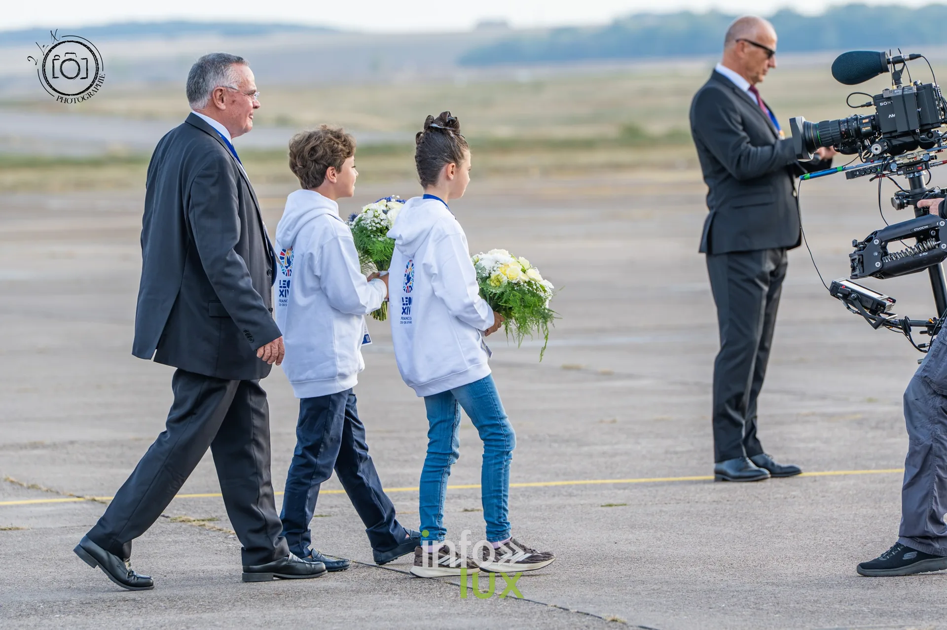 Deux enfants portant des bouquets de fleurs sur le tarmac avant l’arrivée du pape Léon XIV