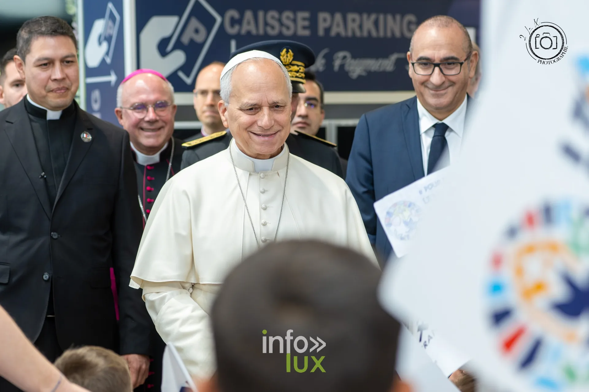 Le pape Léon XIV accueilli par des enfants agitant des drapeaux dans le hall de l’aéroport