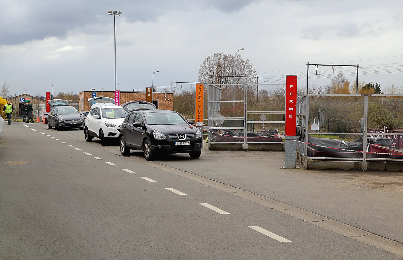 Entrée d'un recyparc en Wallonie, avec ses conteneurs et une file de voitures