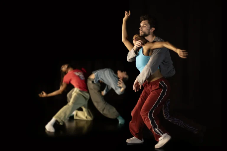 Cinq danseurs de Reflections on monsters sur un plateau noir, un duo enlace au premier plan, trois danseurs cambres a l arriere