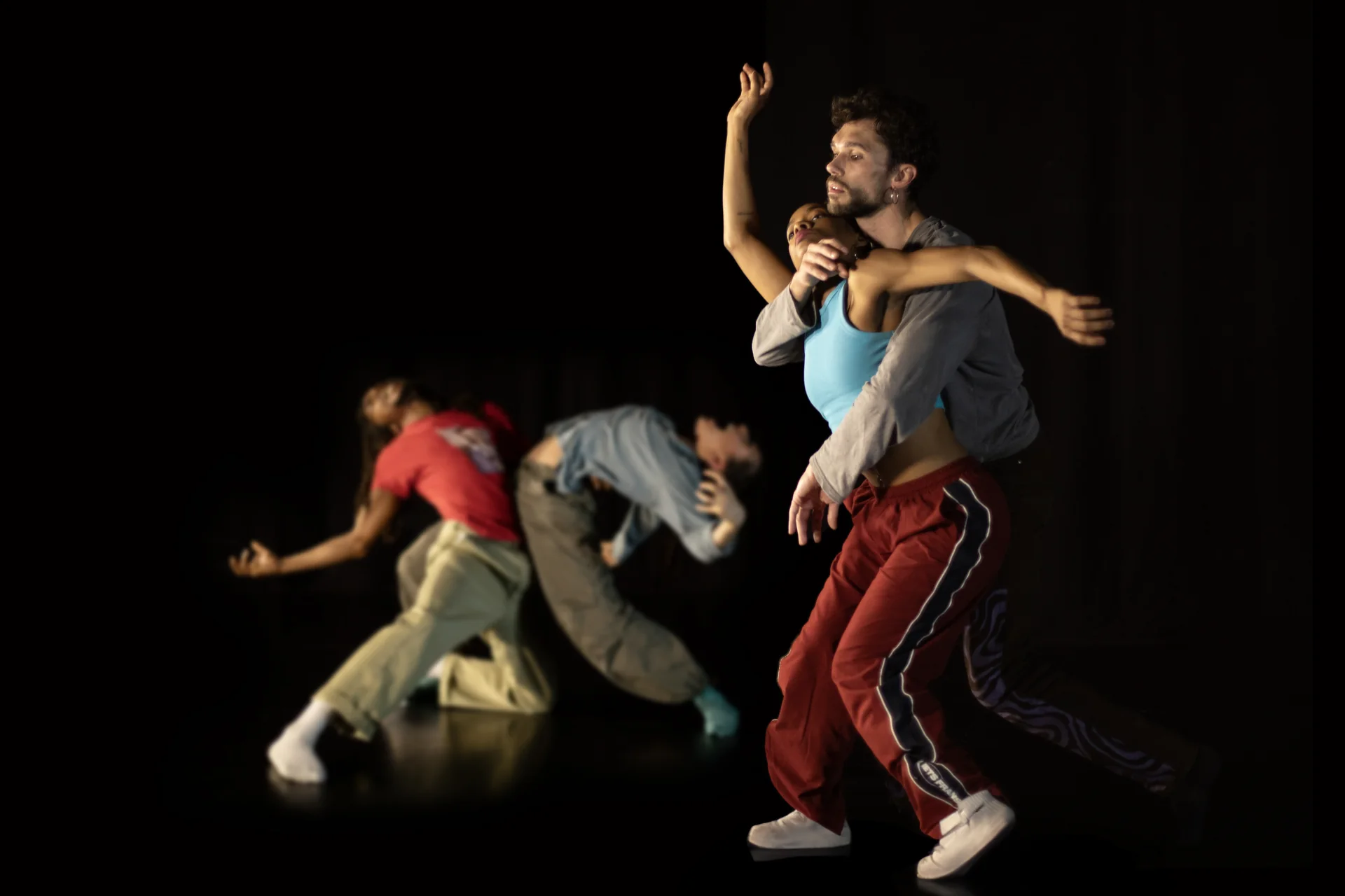 Cinq danseurs de Reflections on monsters sur un plateau noir, un duo enlacé au premier plan