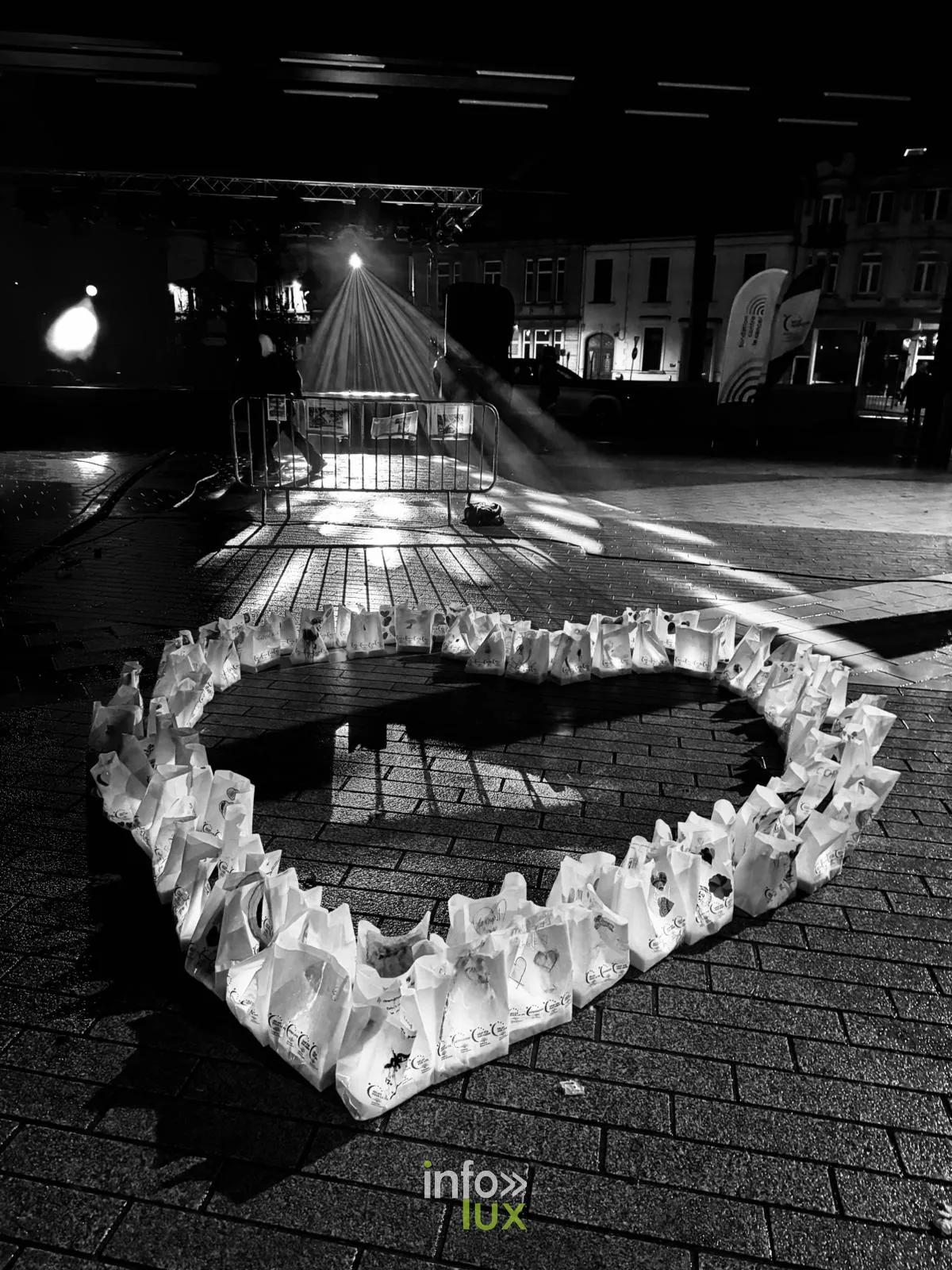 Un cœur formé de sacs-bougies éclairés, la nuit, sur la place Léopold à Arlon, en noir et blanc