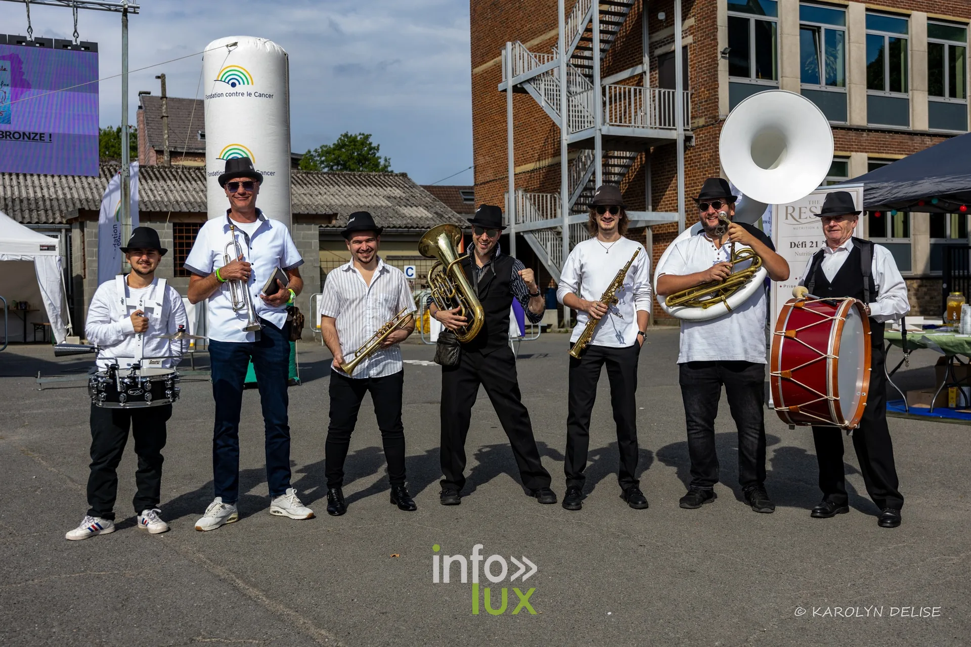 Fanfare en chemise blanche et chapeau noir au village du Relais, Relais pour la Vie de Nivelles 2026