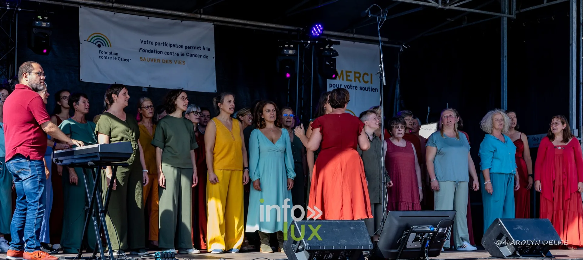 Chorale en robes colorées sur la scène, cérémonie de clôture, Relais pour la Vie de Nivelles 2026