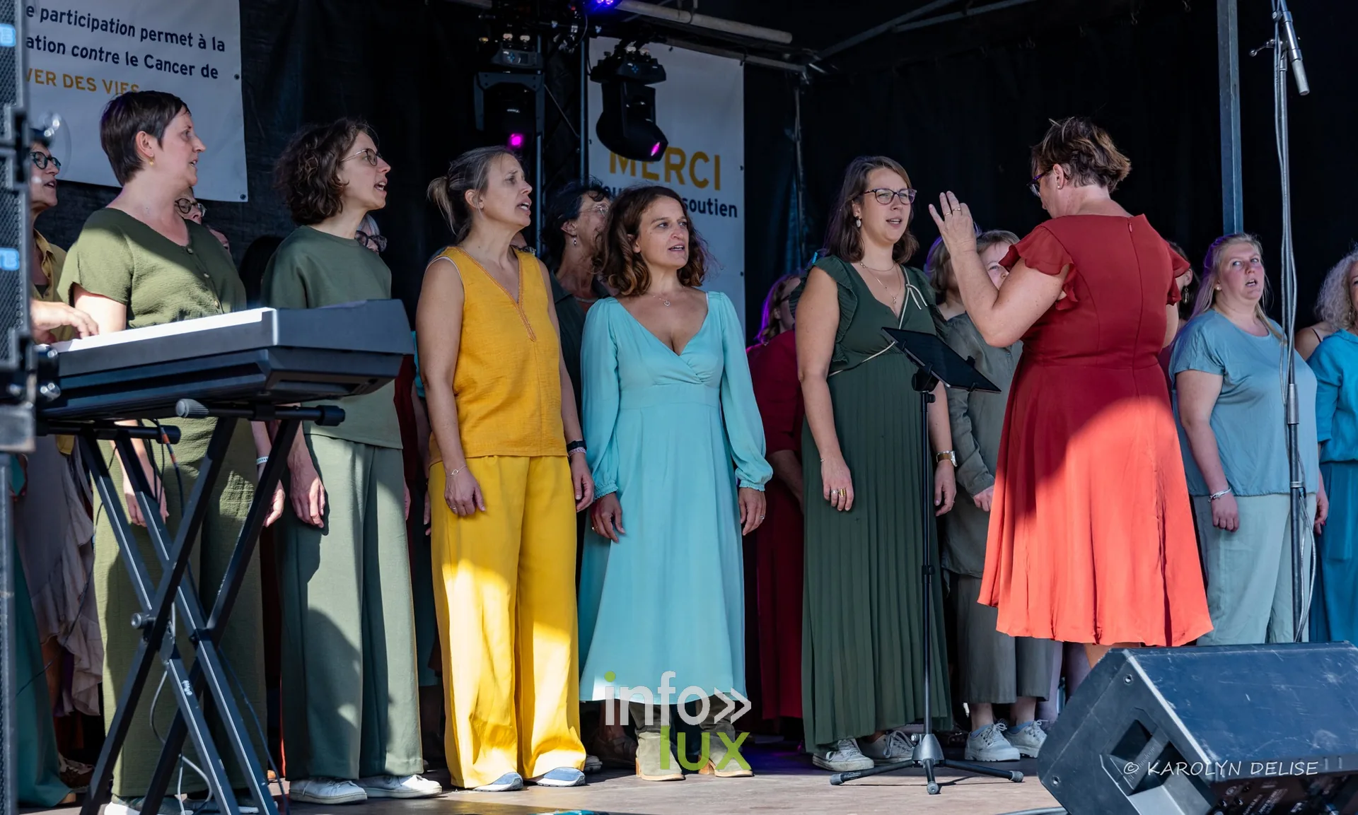 Chorale en robes colorées sur la scène, cérémonie de clôture, Relais pour la Vie de Nivelles 2026
