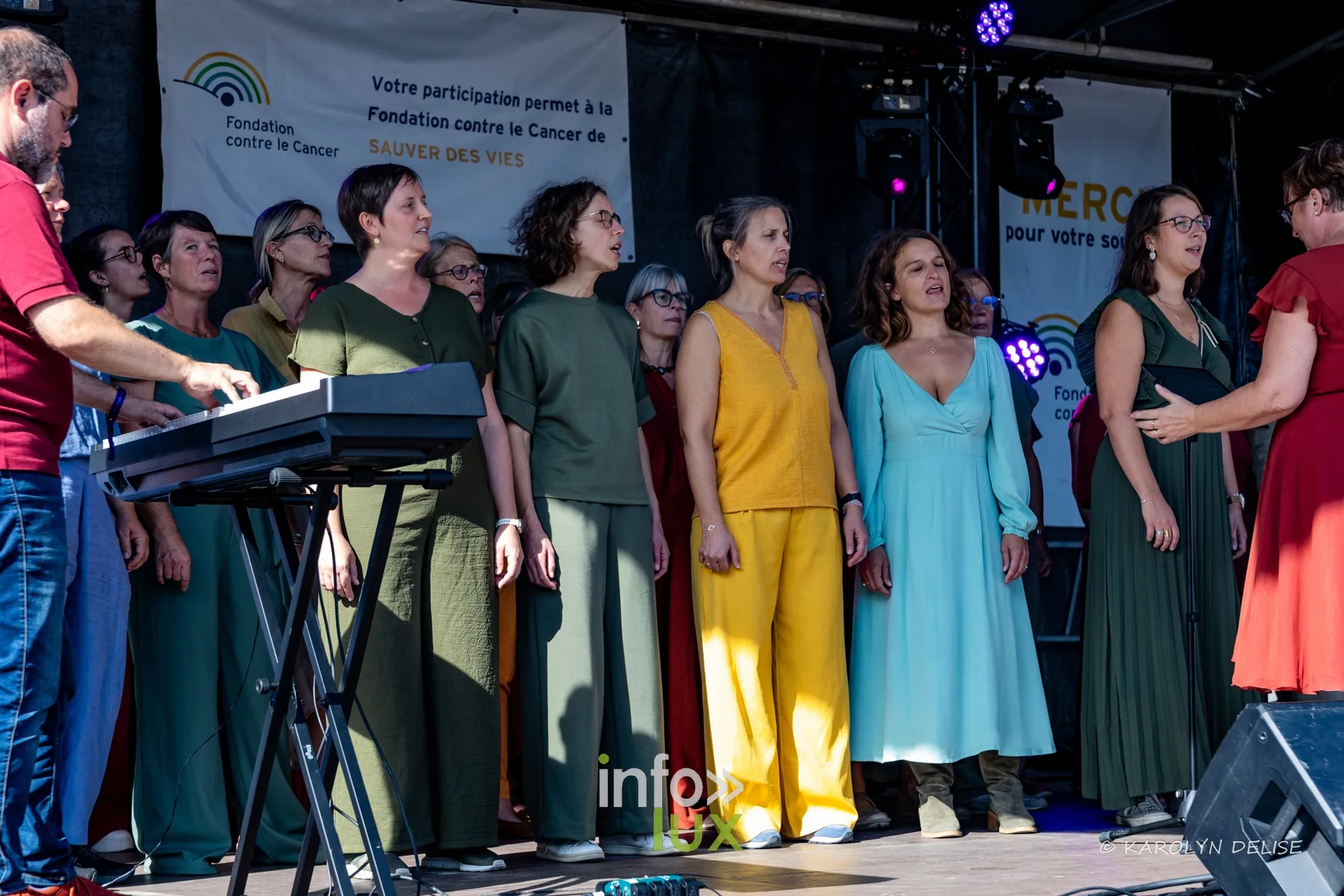 Chorale en robes colorées sur la scène, cérémonie de clôture, Relais pour la Vie de Nivelles 2026