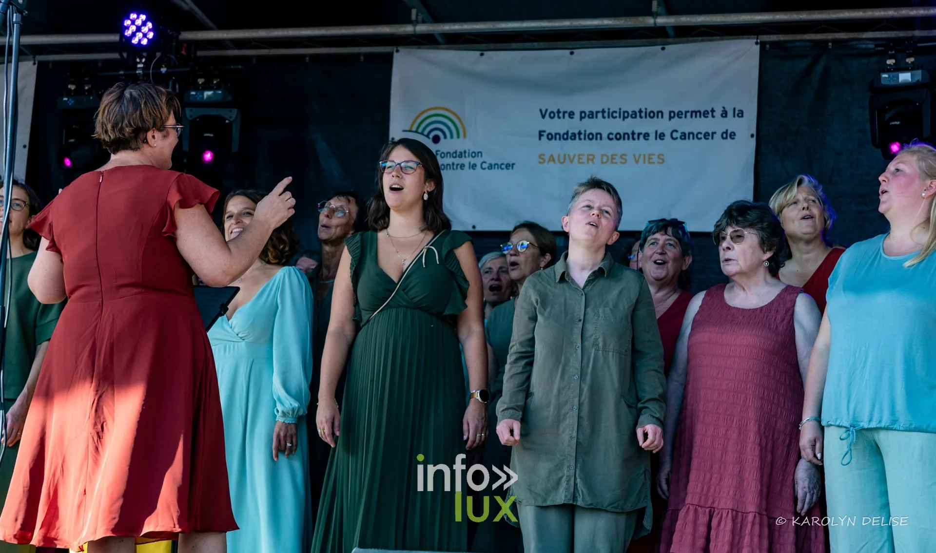 Chorale en robes colorées sur la scène, cérémonie de clôture, Relais pour la Vie de Nivelles 2026