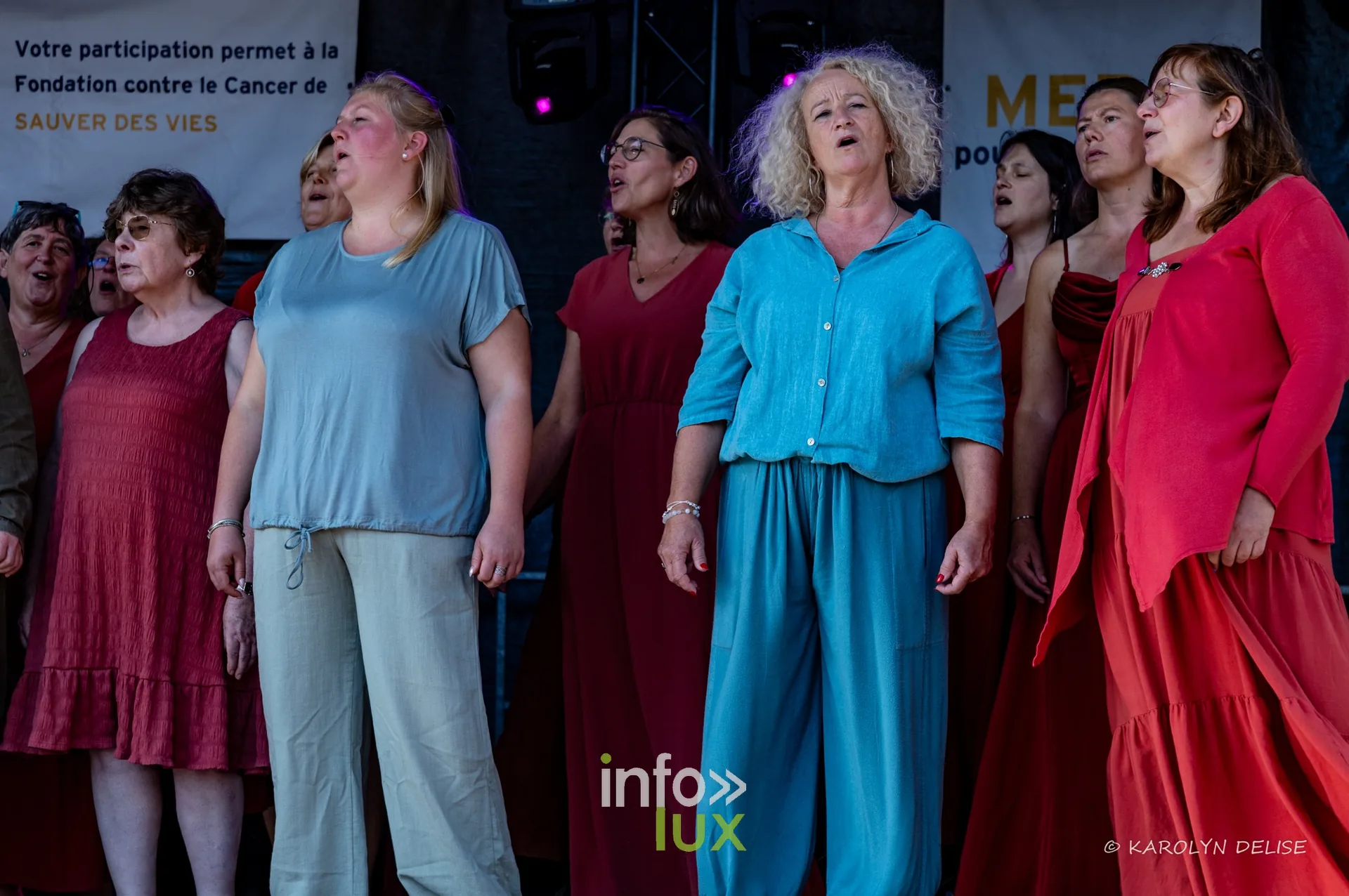 Chorale en robes colorées sur la scène, cérémonie de clôture, Relais pour la Vie de Nivelles 2026