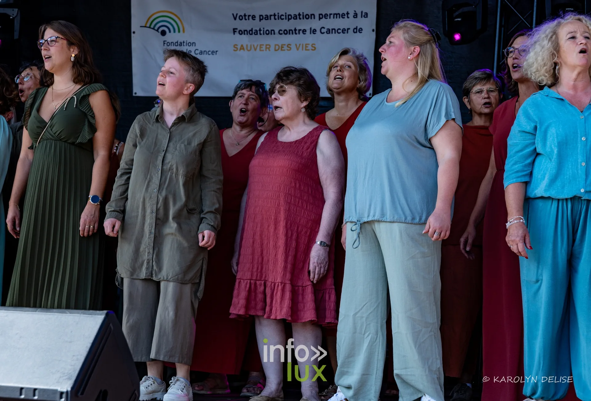 Chorale en robes colorées sur la scène, cérémonie de clôture, Relais pour la Vie de Nivelles 2026