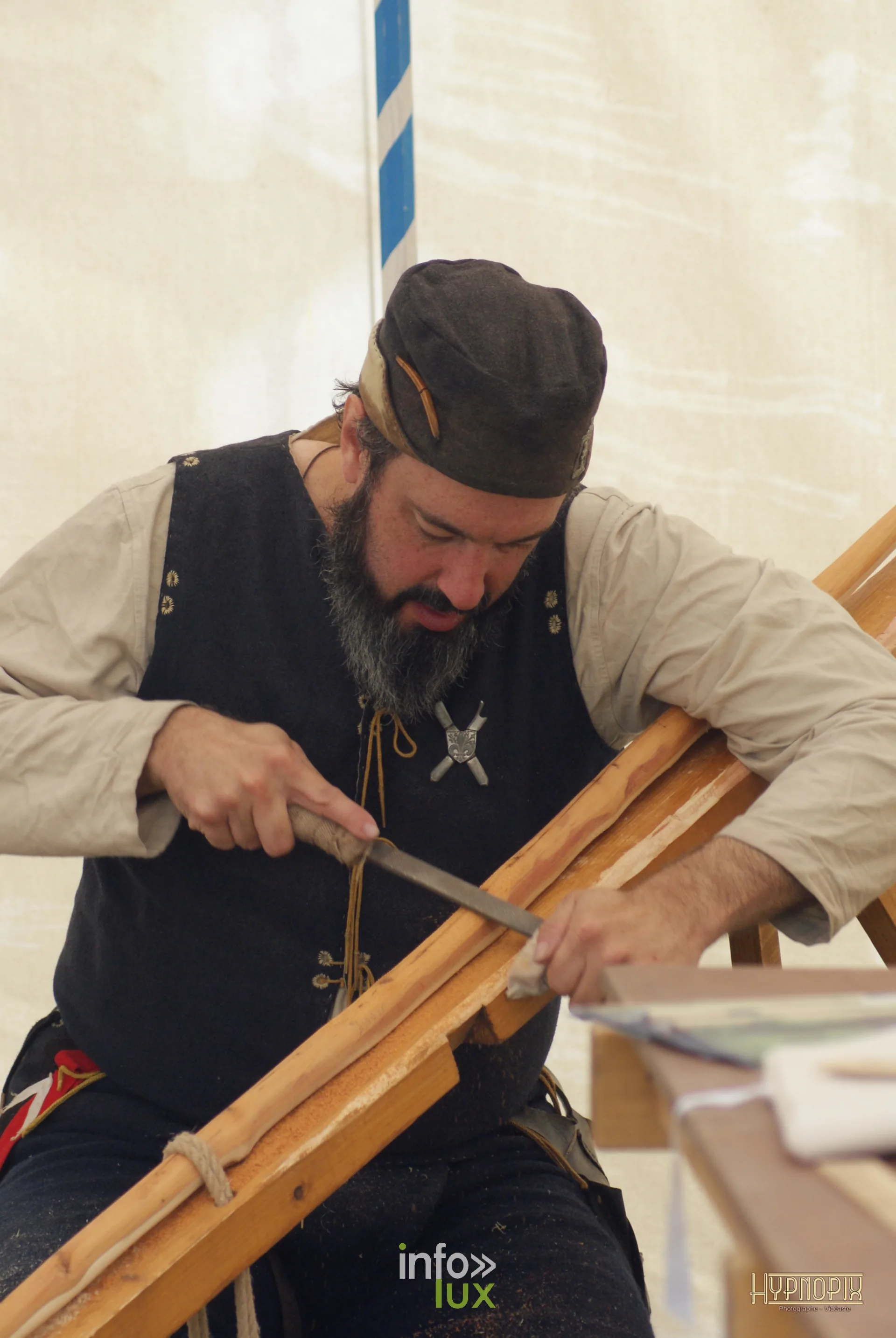 Artisan travaillant une pièce de bois au campement des Rencontres Médiévales de Braine-le-Château 2026