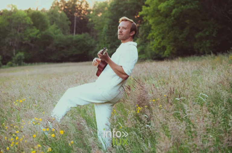 Romain Helvétius, guitare à la main dans un champ, pour son album Univers