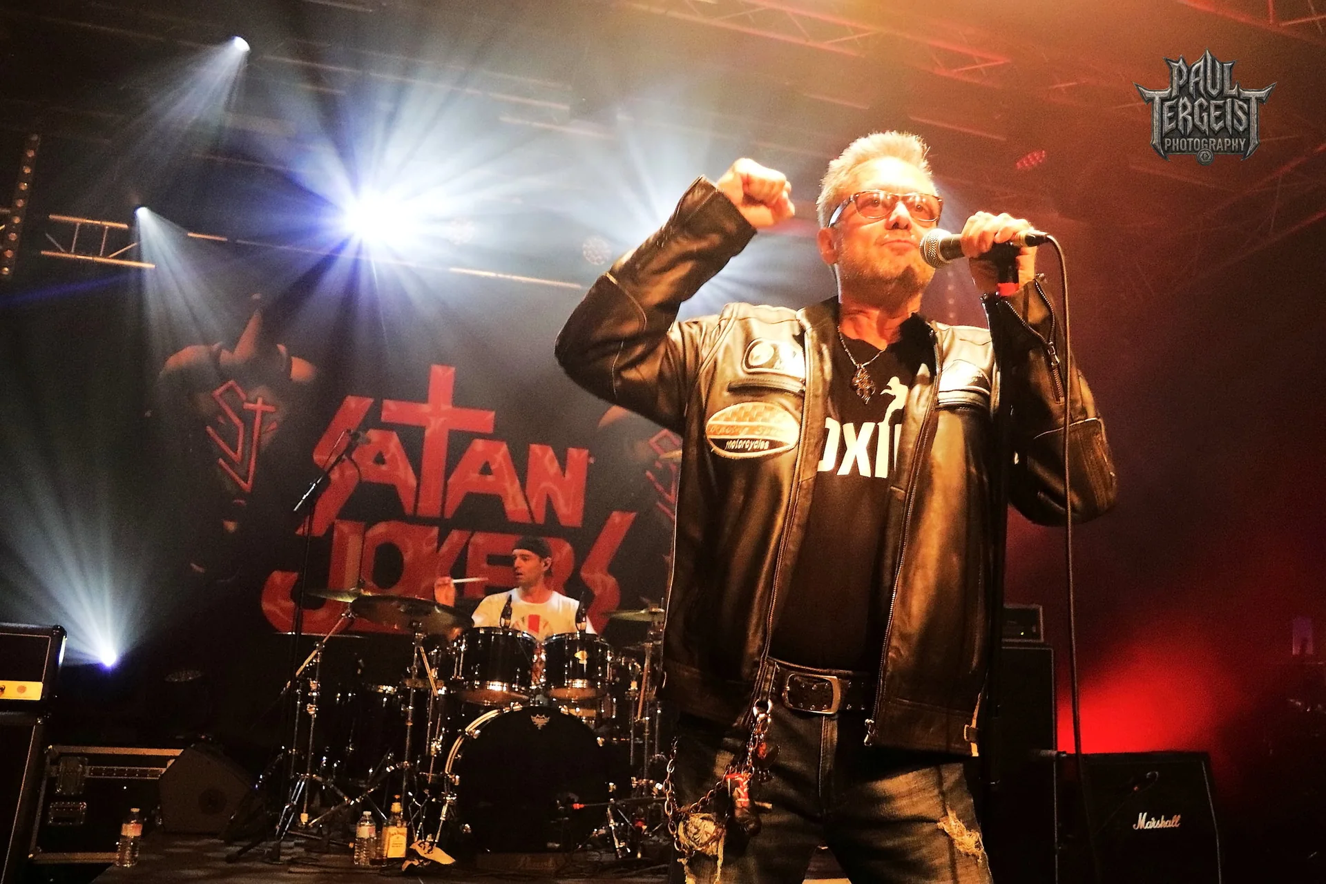 Chanteur de Satan Jokers devant la banniere du groupe au Golden Age Rock Festival 2023