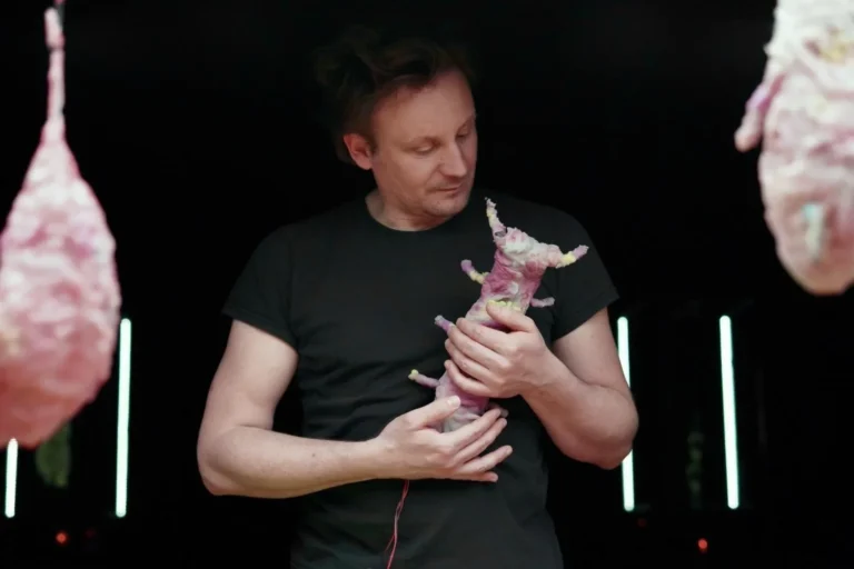 Ugo Dehaes penché sur une grande table où évoluent ses petites créatures robotiques, devant le public de Simple Machines
