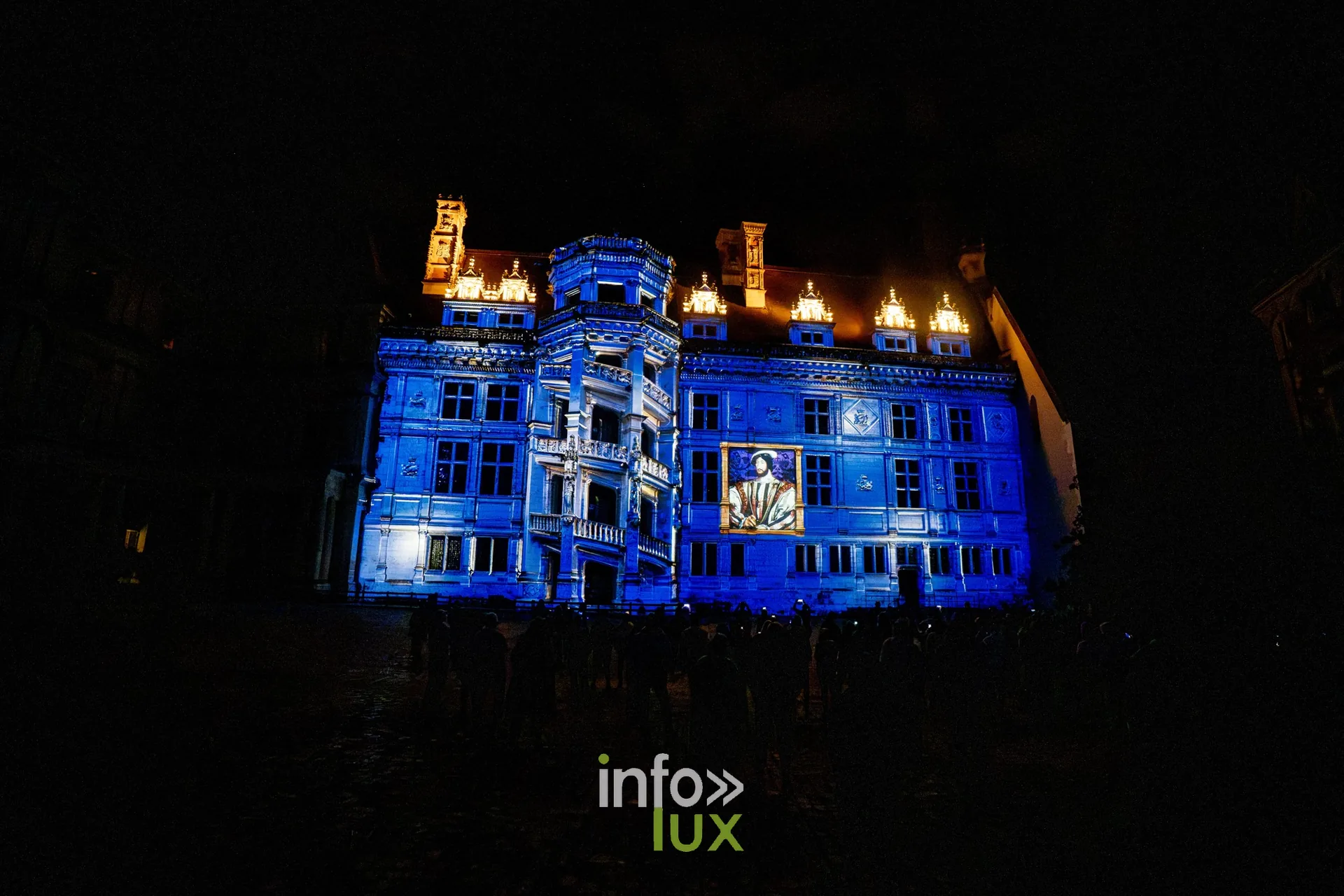 Aile du château de Blois projetée en bleu, toits éclairés d'or