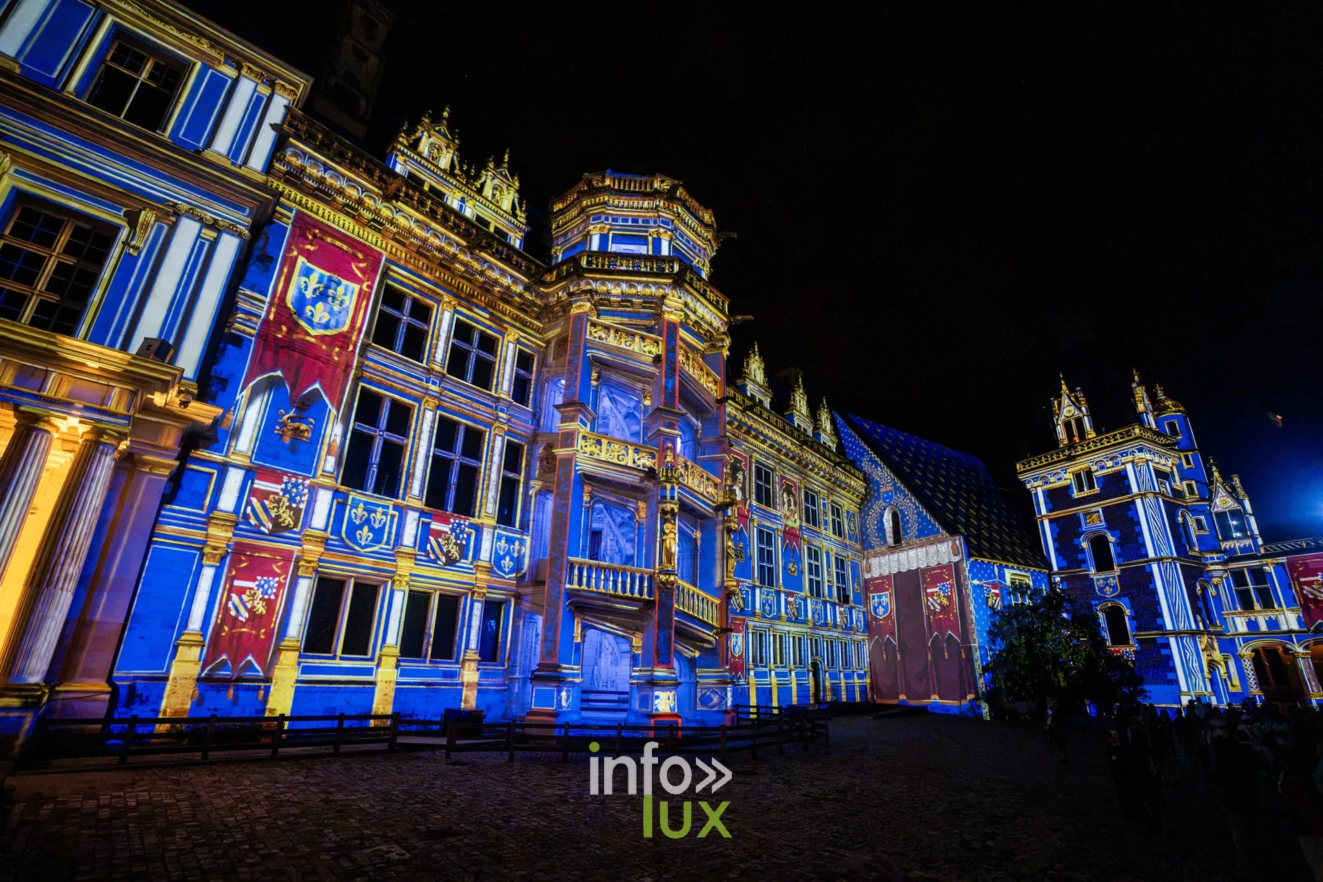 Perspective sur les ailes du château de Blois habillées de bannières rouges et bleues
