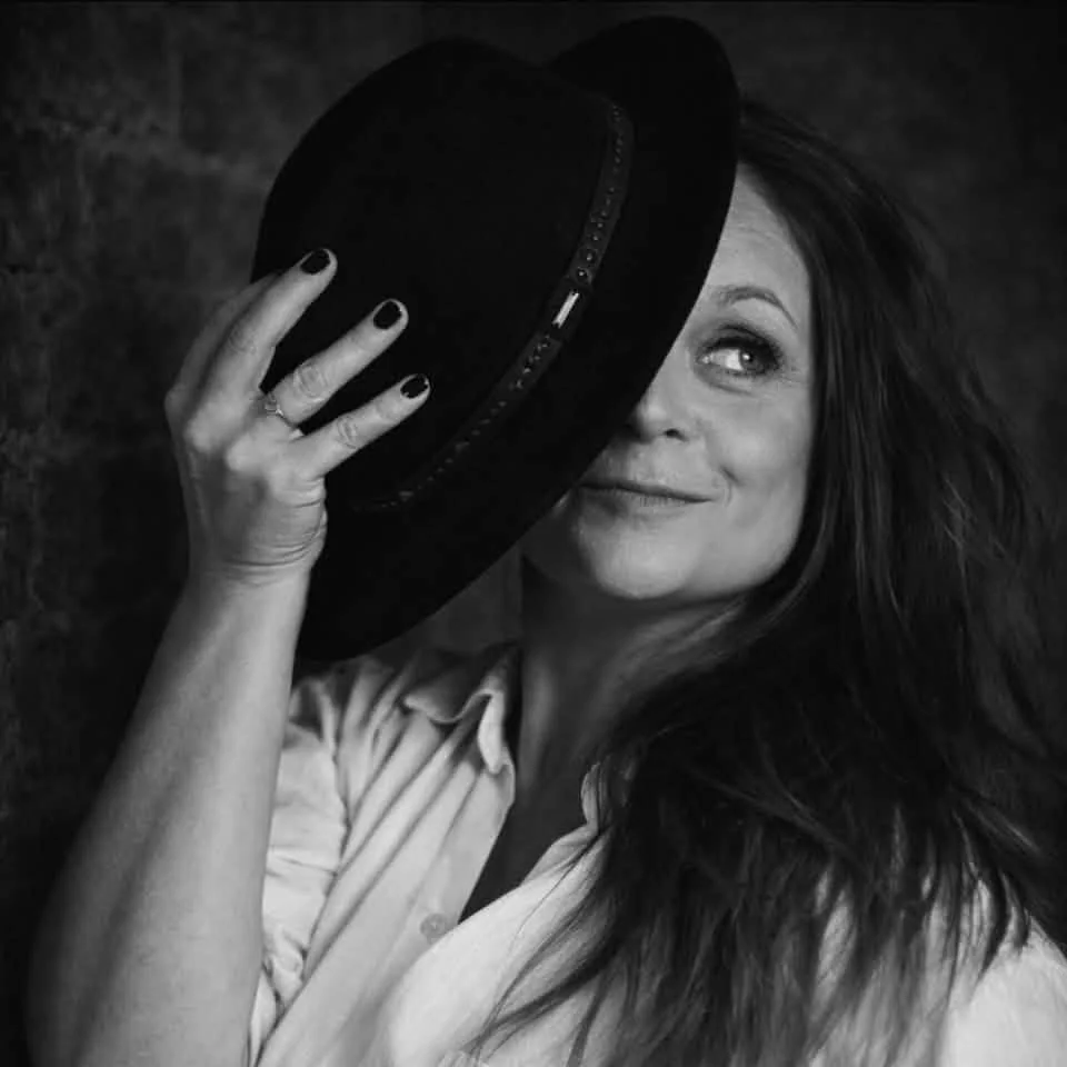 Portrait en noir et blanc de la chanteuse Stéfany Rydel, un chapeau devant le visage