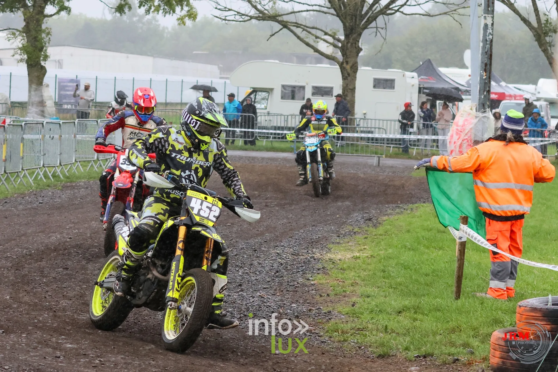 Supermotard de Battice 2026, Herve (province de Liège) : pilote n°452 dans la partie terre mouillée, un commissaire drapeau en main