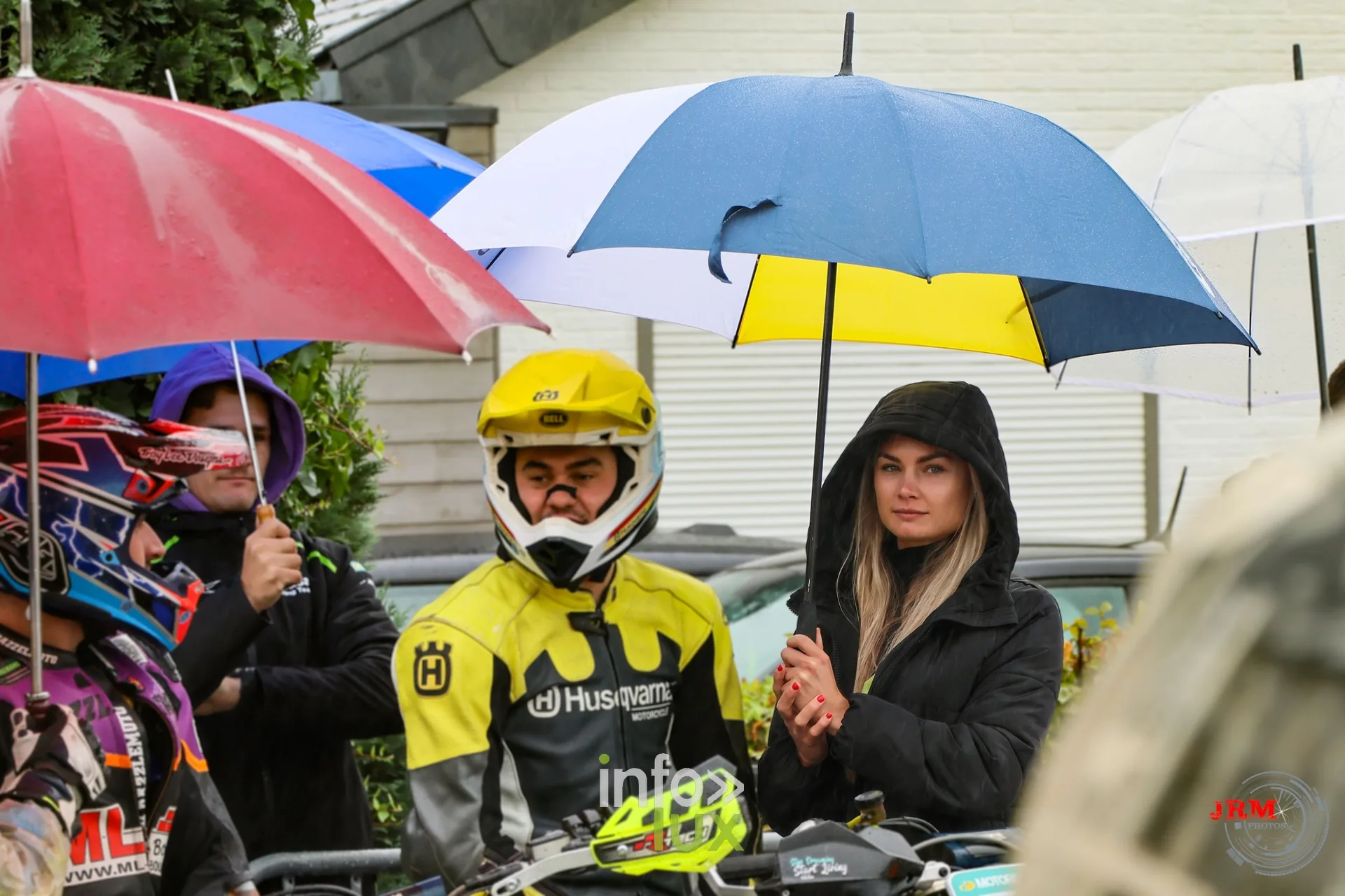 Supermotard de Battice 2026, Herve (province de Liège) : un pilote casqué et des spectateurs abrités sous des parapluies en bord de piste