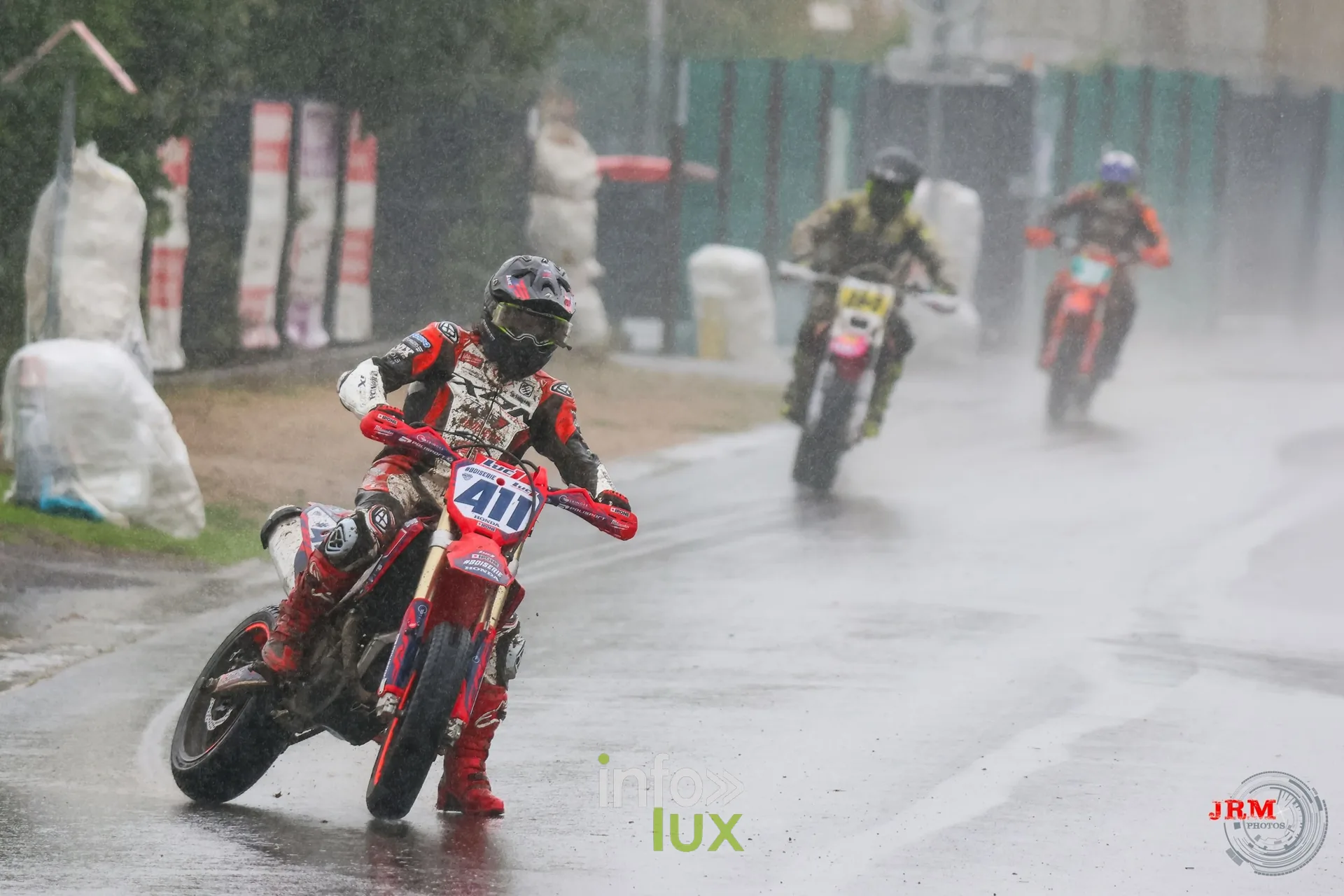 Supermotard de Battice 2026, Herve (province de Liège) : pilote n°411 sur l’asphalte détrempé, deux concurrents derrière lui sous la pluie