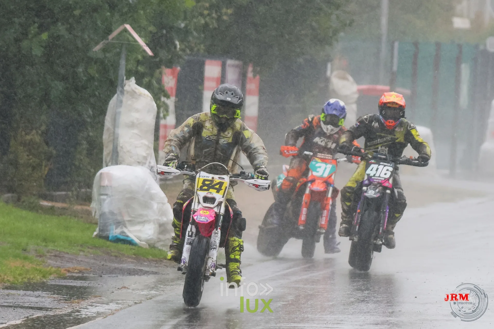 Supermotard de Battice 2026, Herve (province de Liège) : le pilote n°84 devant les n°31 et n°416 dans un virage d’asphalte sous la pluie