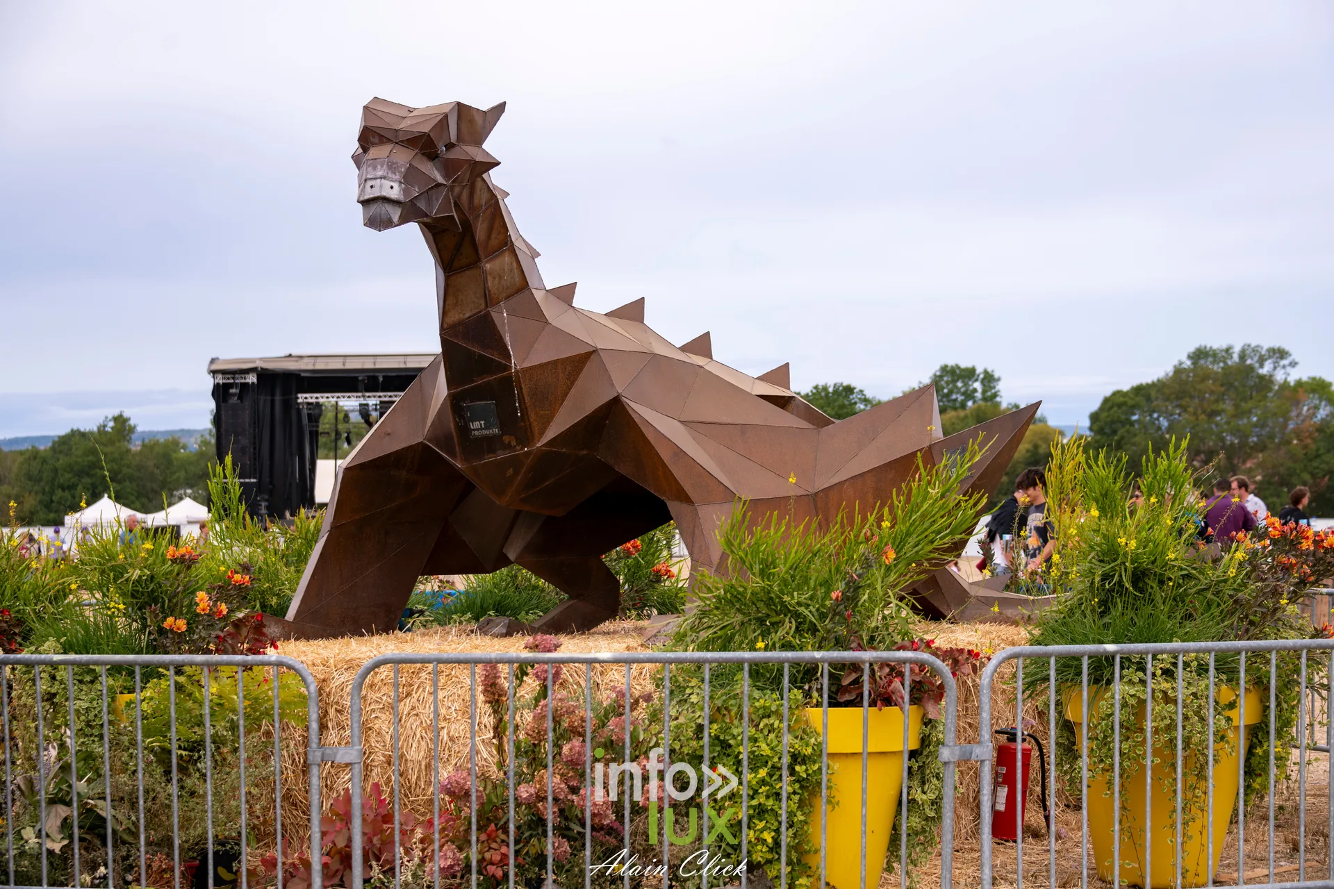 Sculpture de dragon en metal rouille dans un massif fleuri aux Terres de Jim 2026