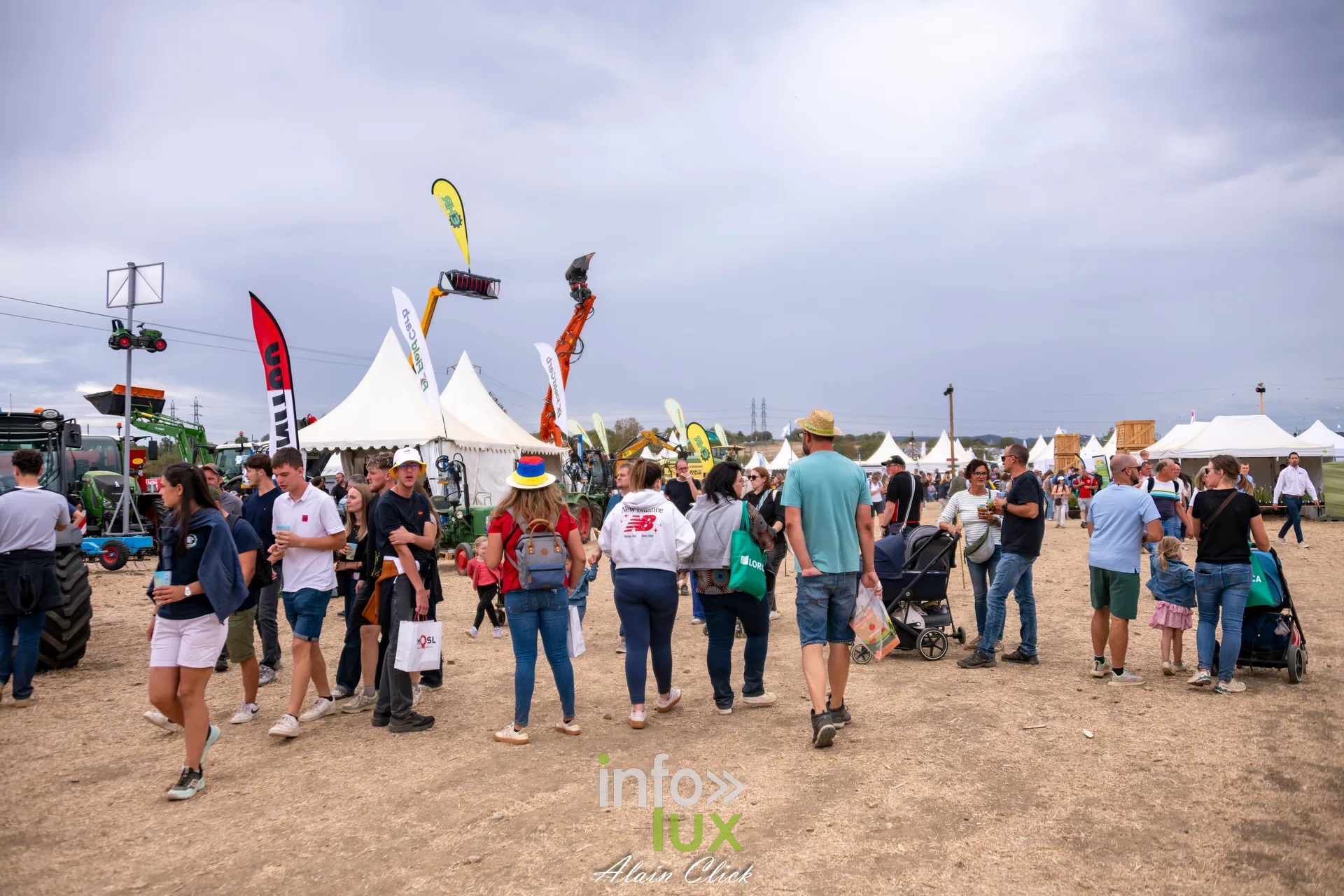 Visiteurs deambulant entre les stands de materiel agricole aux Terres de Jim