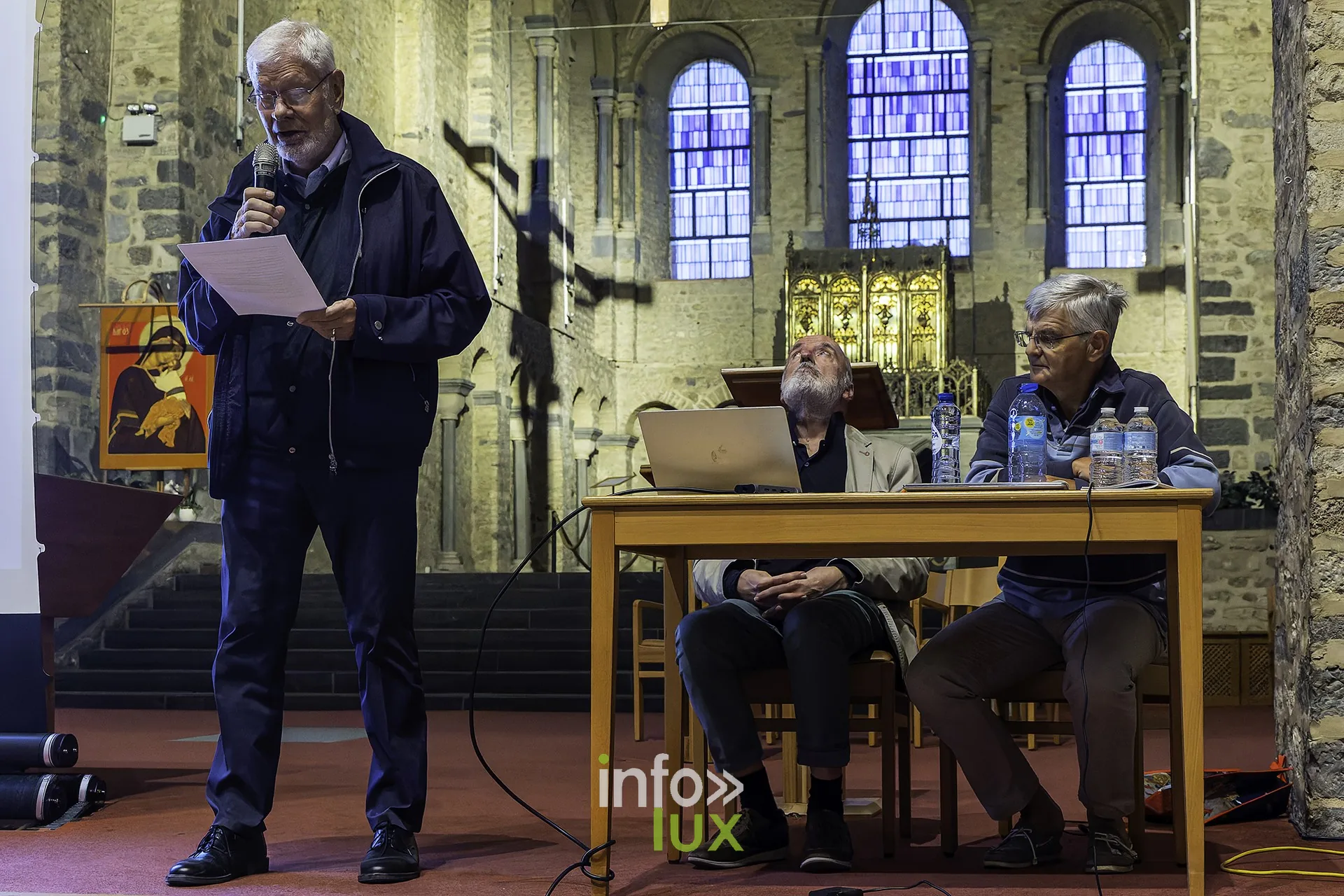 L’historien lit son exposé, devant les vitraux de la collégiale