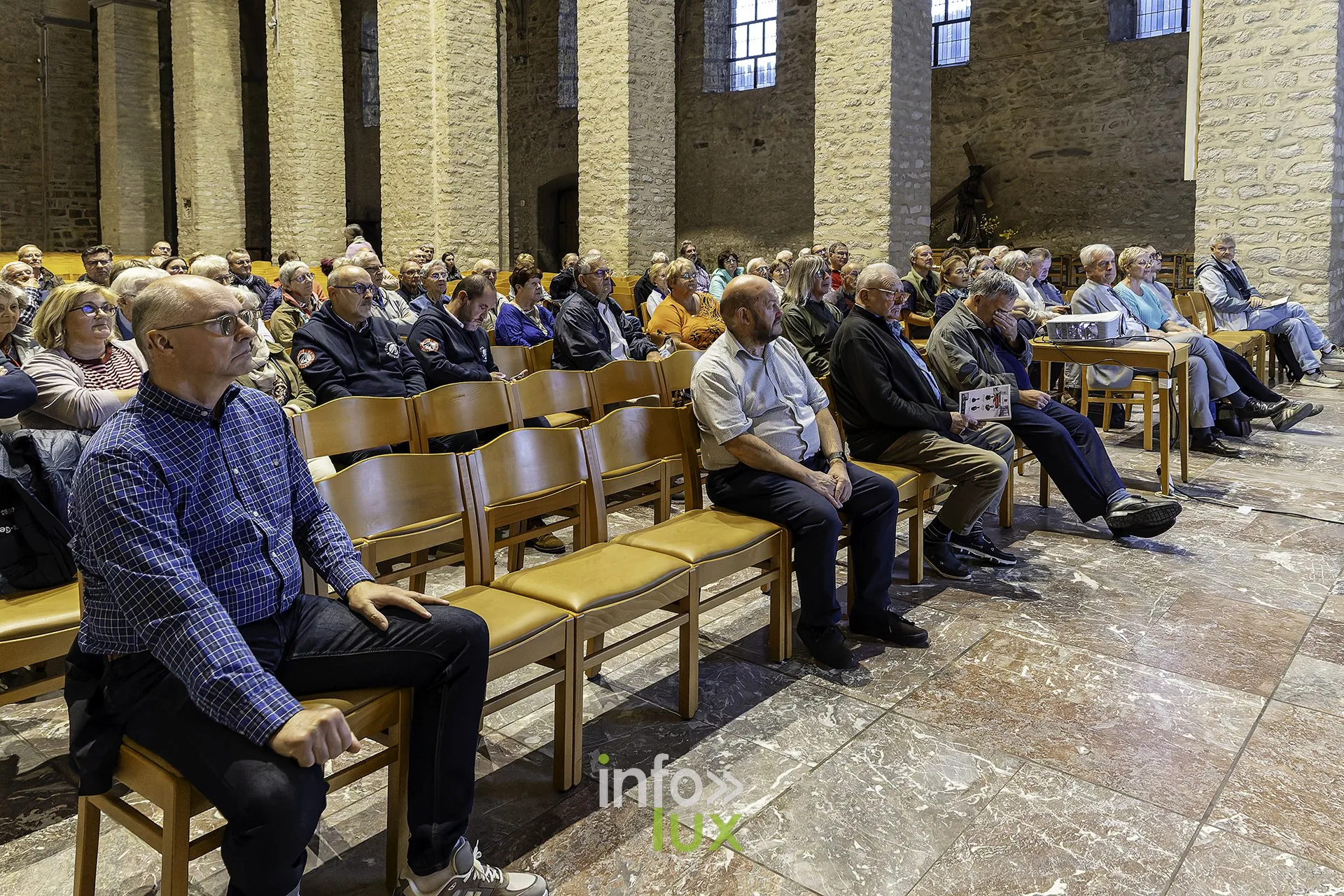 Le public assis dans la nef écoute le premier exposé