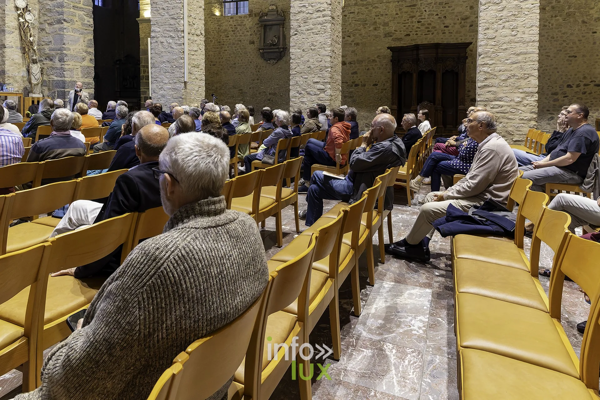 Spectateurs de dos, attentifs, dans la nef