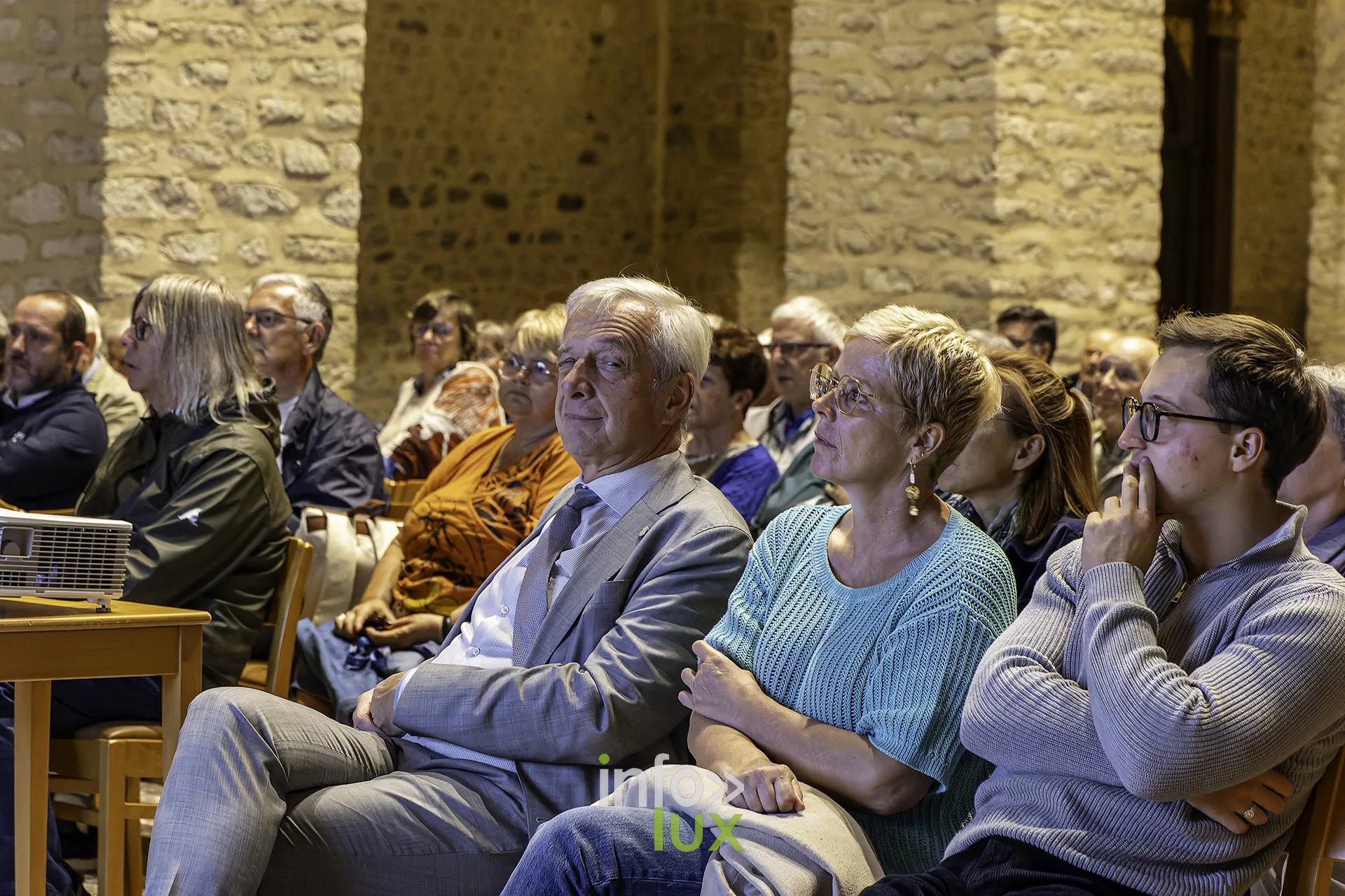 Le public écoute, une femme sourit au premier plan