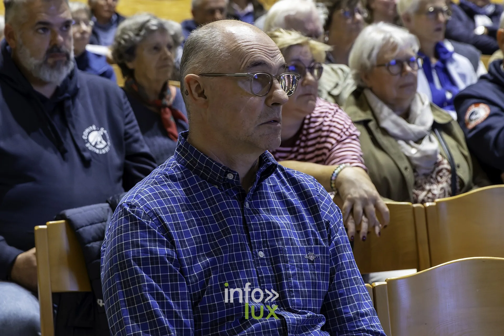 Spectateurs attentifs, un homme en veste bleue au premier plan