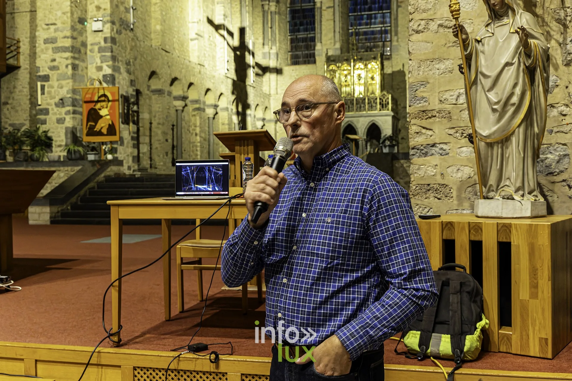 L’intervenant au pupitre commente une image, ordinateur ouvert