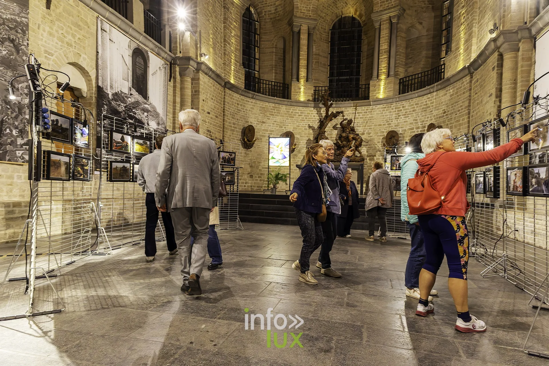 Visiteurs devant les panneaux photo de l’exposition, dans le chœur
