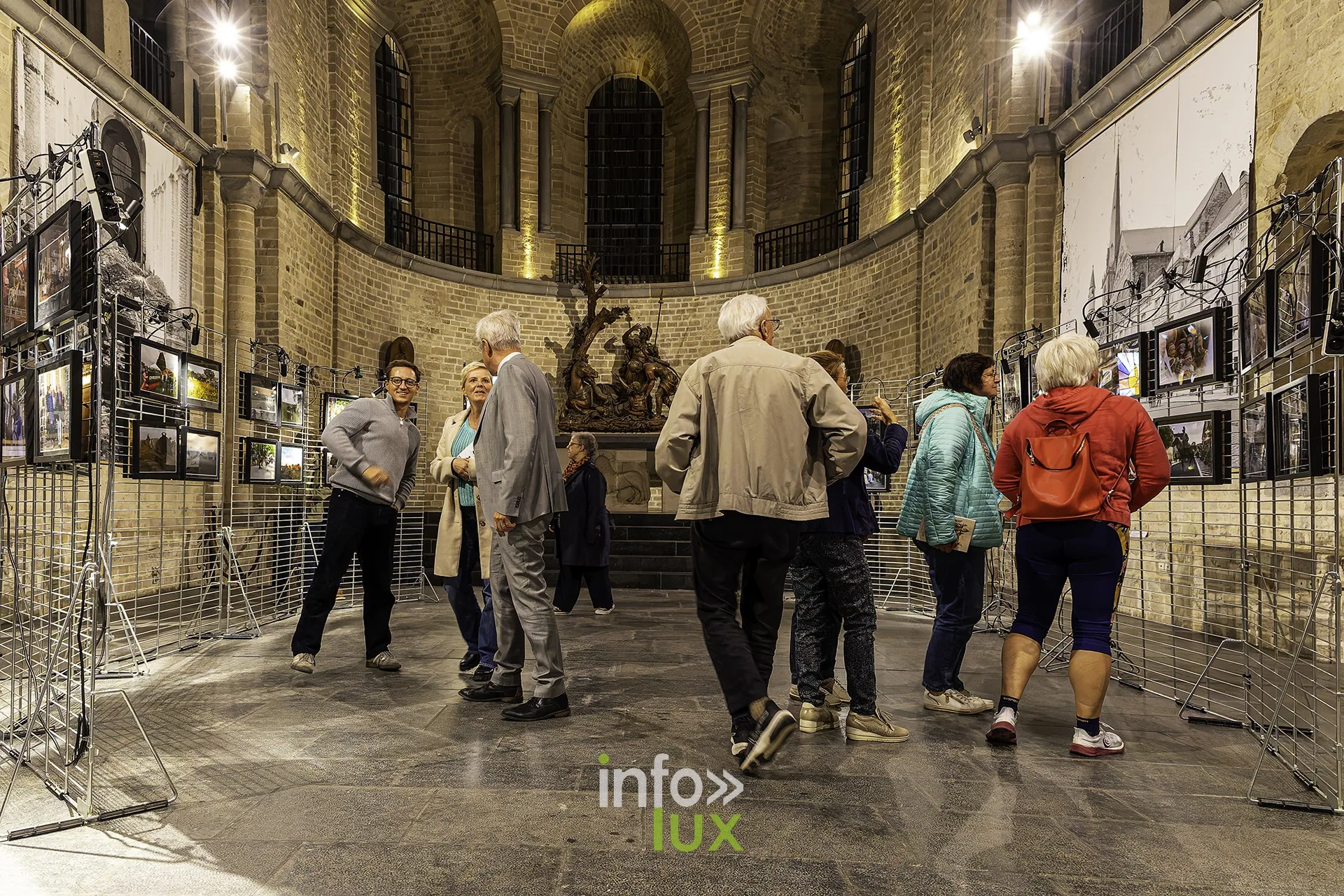 Groupe de visiteurs devant les photos du Tour, dans le chœur de la collégiale