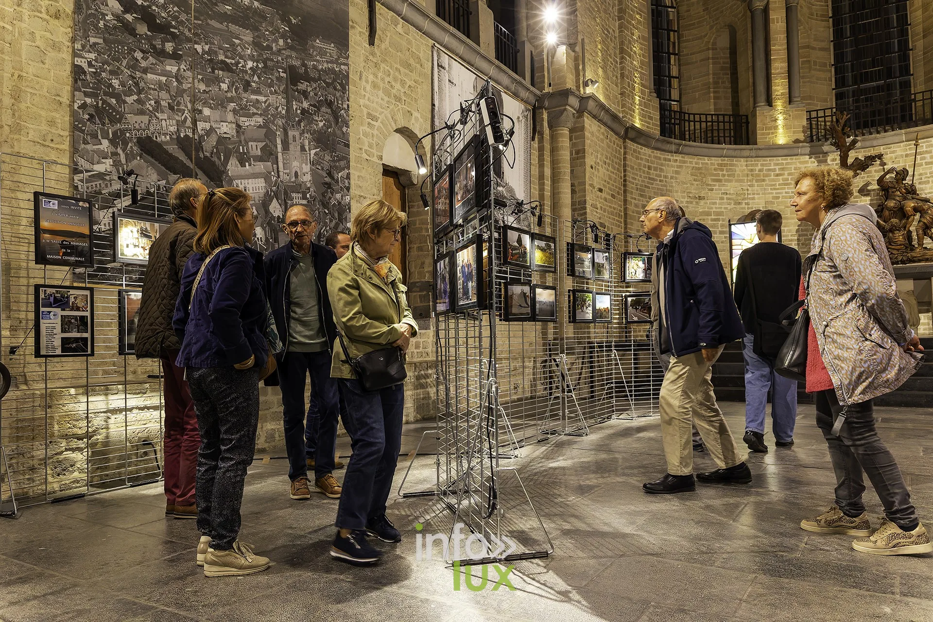 Visiteurs de dos regardant les photographies exposées sur grilles