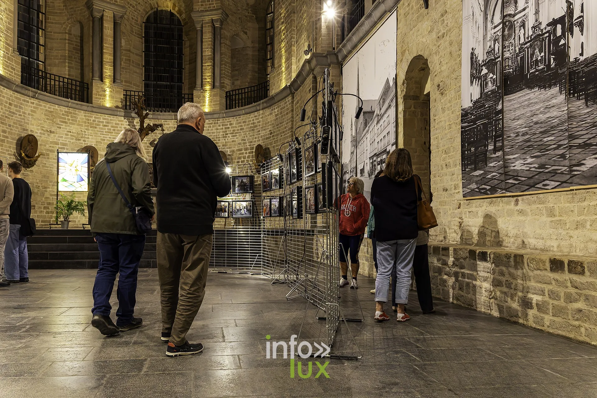 Visiteurs parcourant les allées de l’exposition, sol de pierre