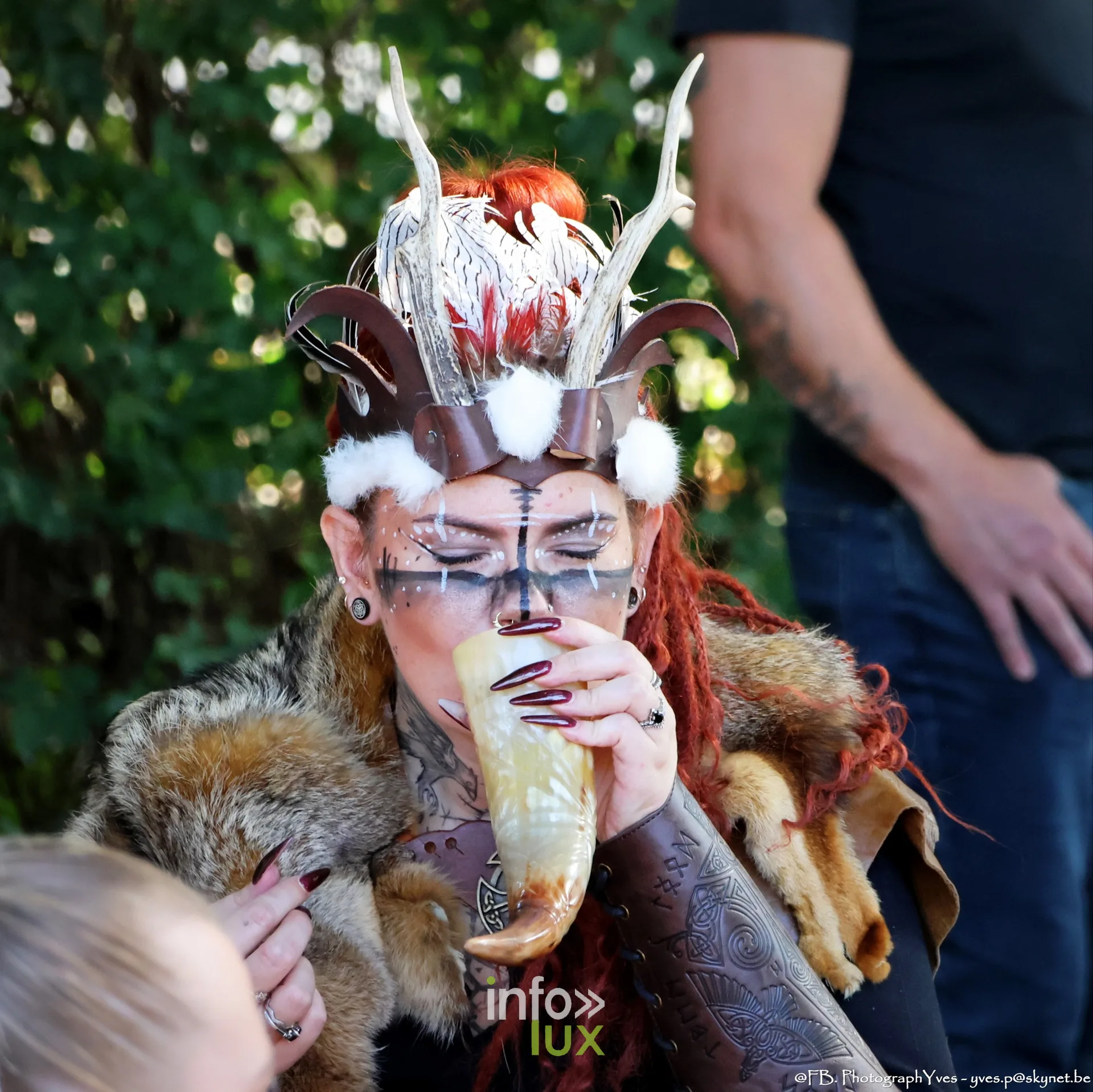 Femme grimée coiffée d’une parure à plumes buvant dans une corne, Valhalla Days 2026