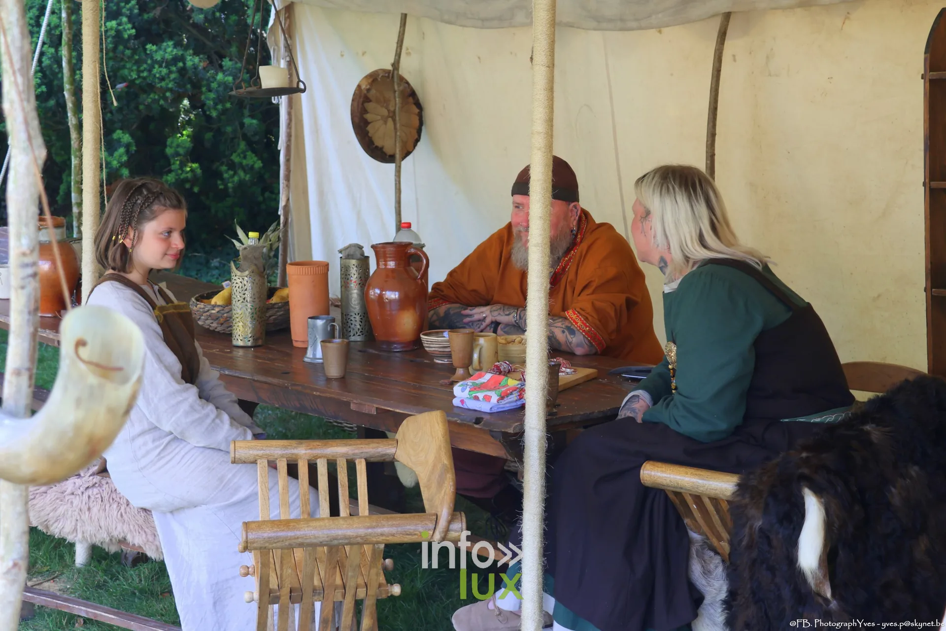 Reconstituteurs attablés sous une tente du campement viking à Ciney