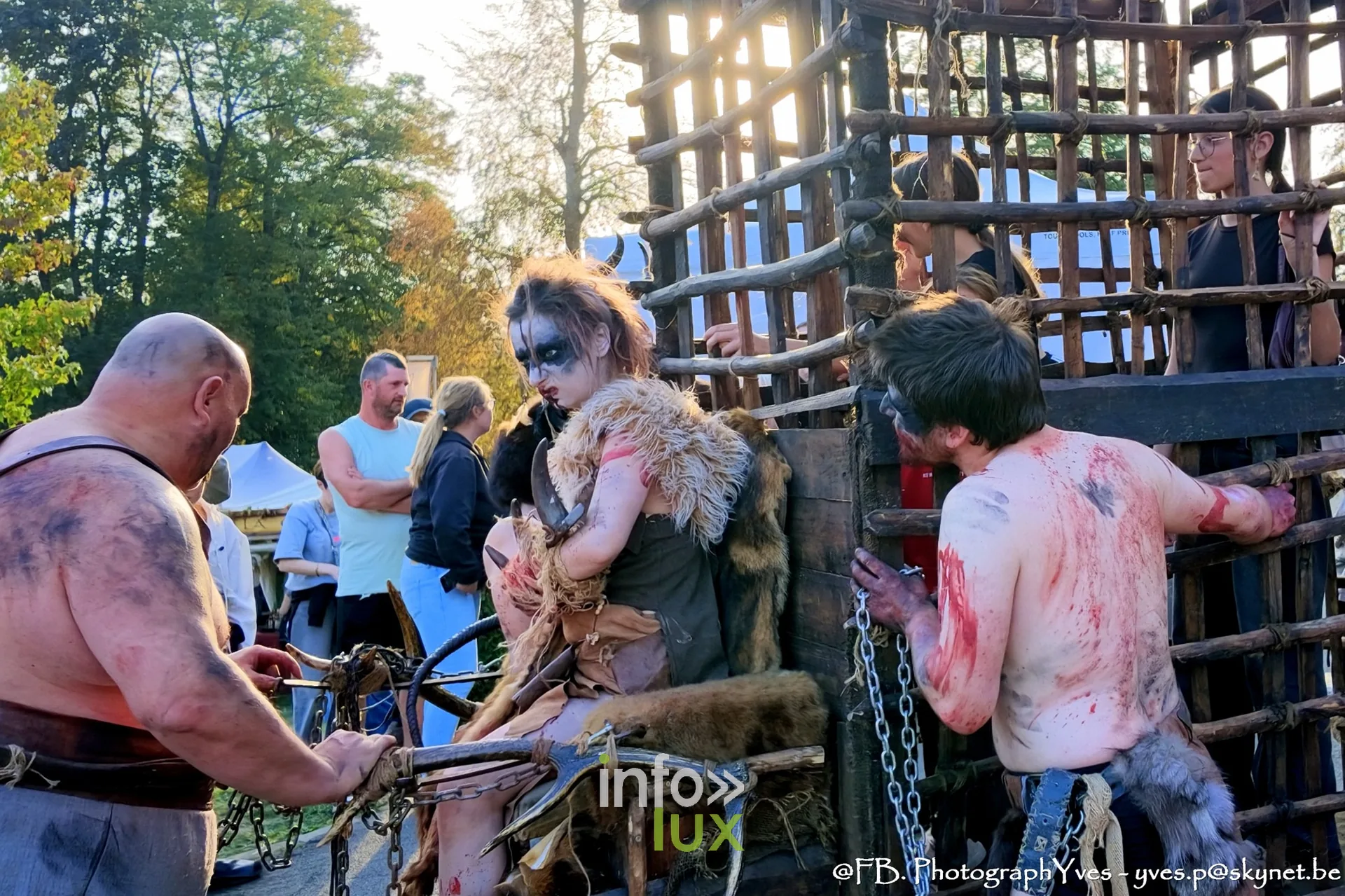 Figurants grimés autour de la cage en bois, dans une allée du parc Saint-Roch