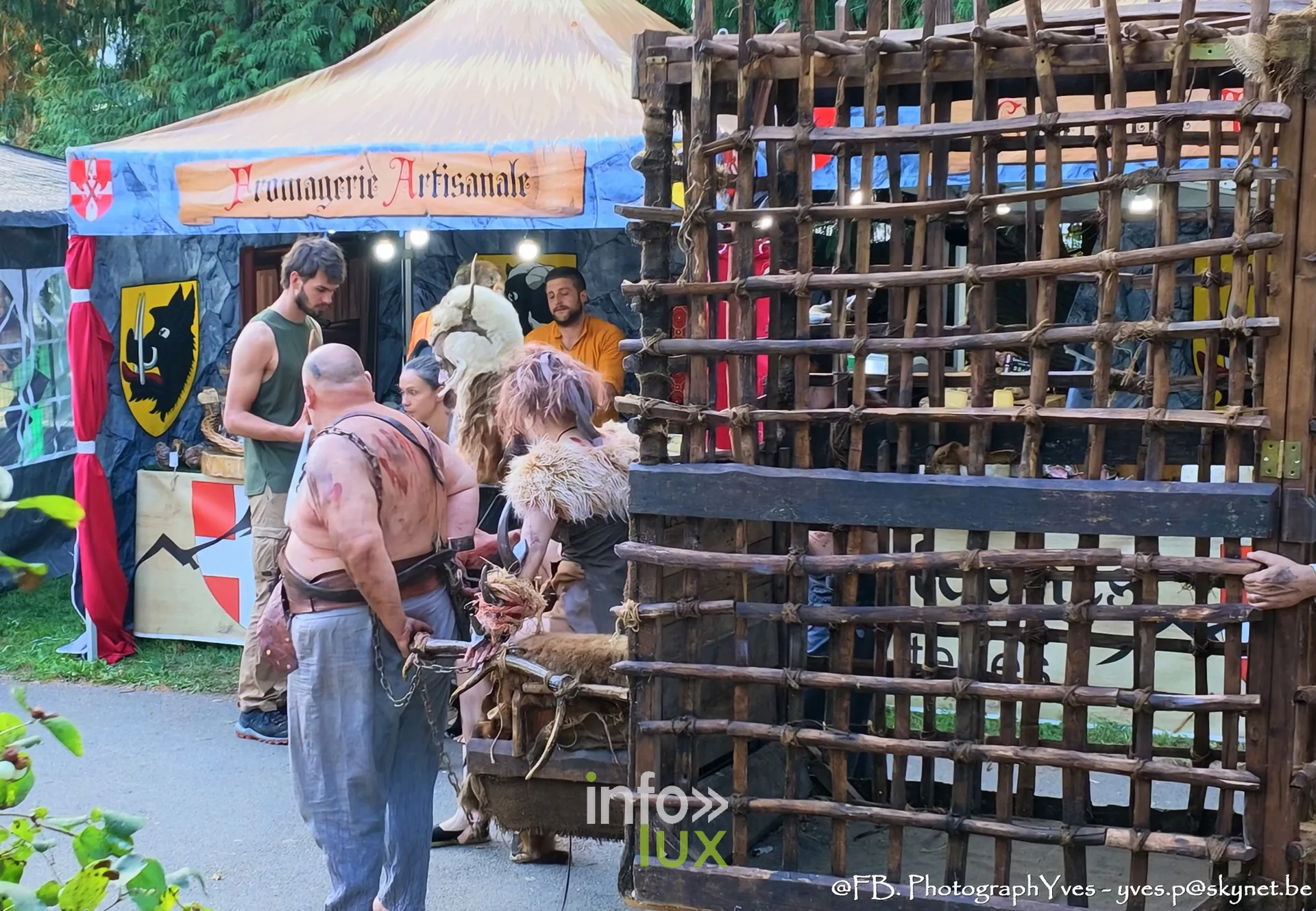 Figurants grimés et cage en bois devant un stand du marché, Valhalla Days 2026