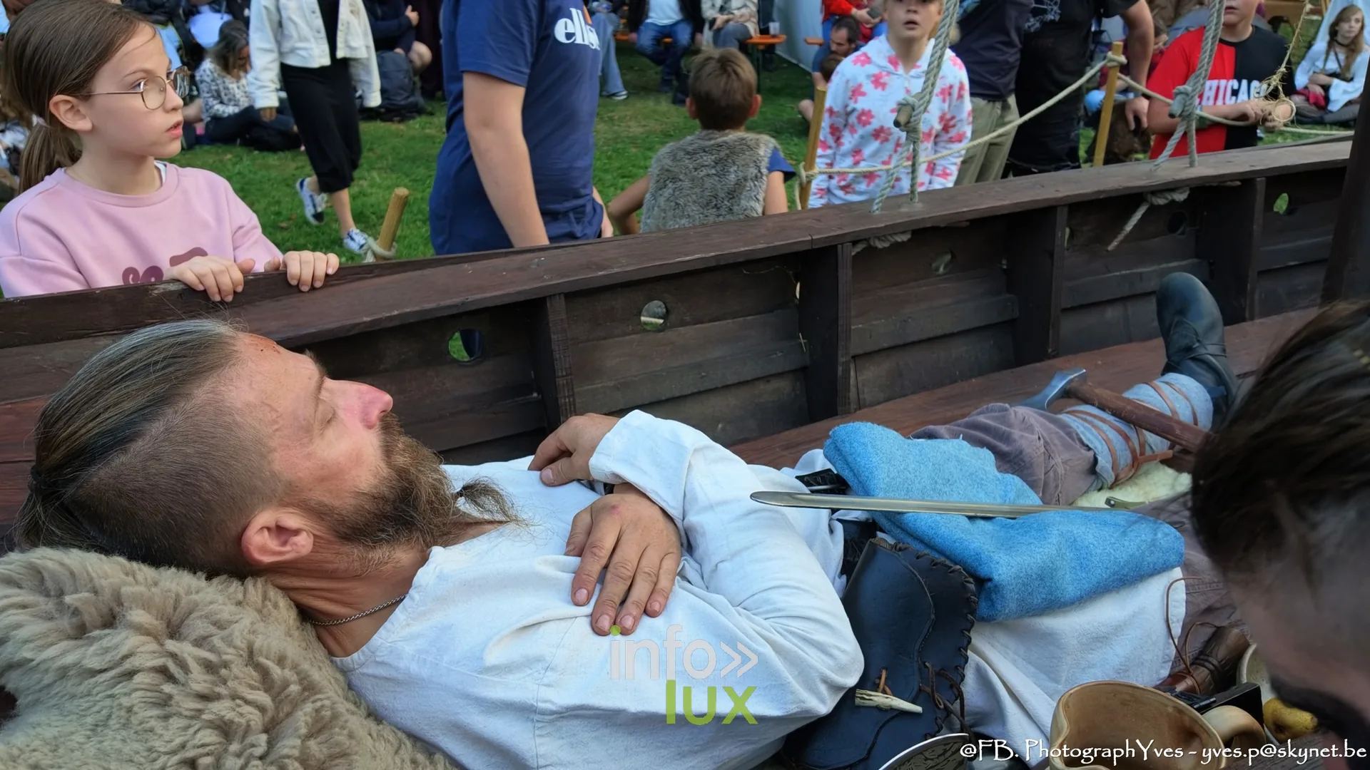 Figurant allongé dans le bateau viking sous le regard des enfants, Valhalla Days 2026