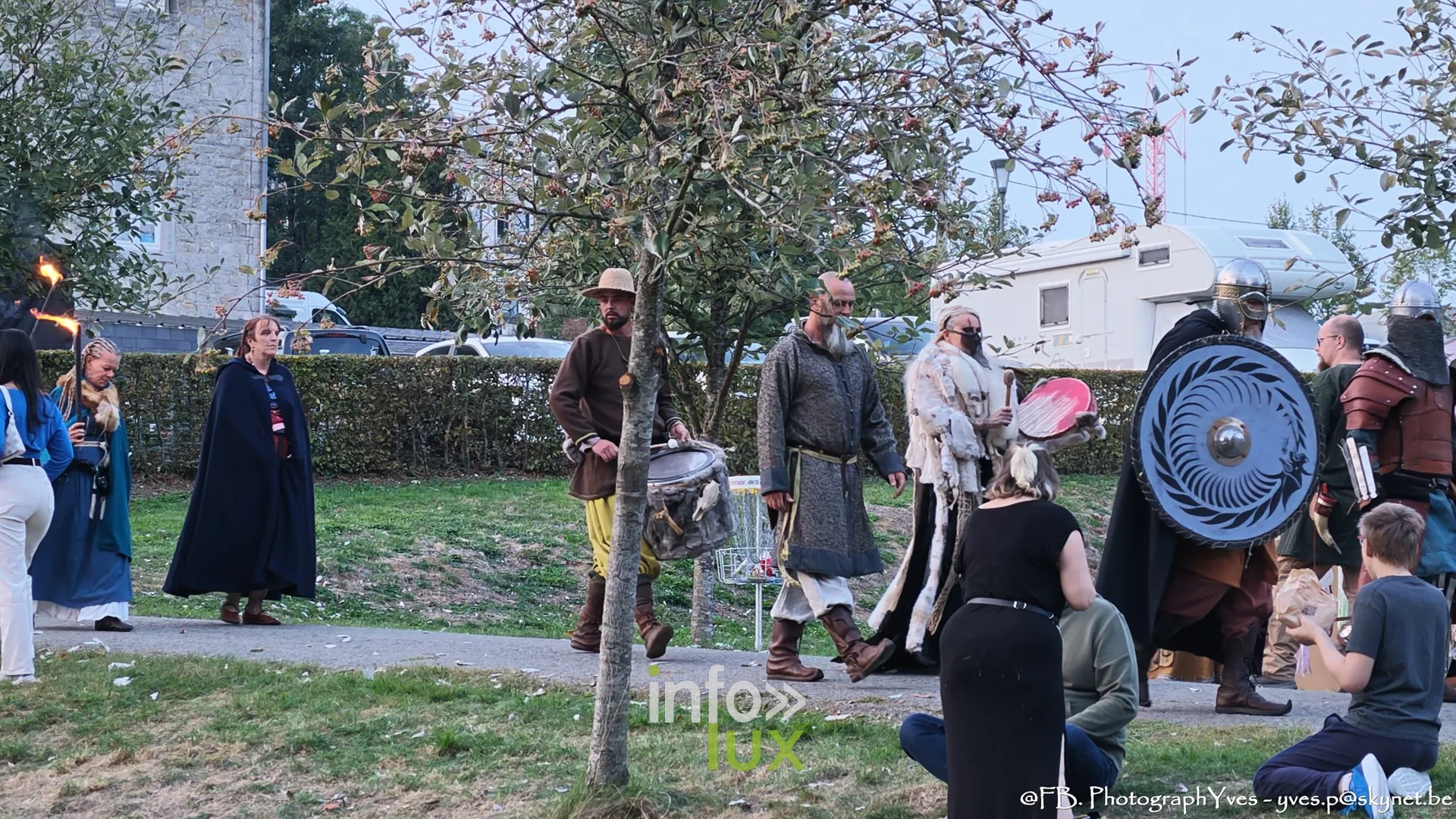 Cortège de reconstituteurs en tenue et boucliers dans une allée du parc Saint-Roch