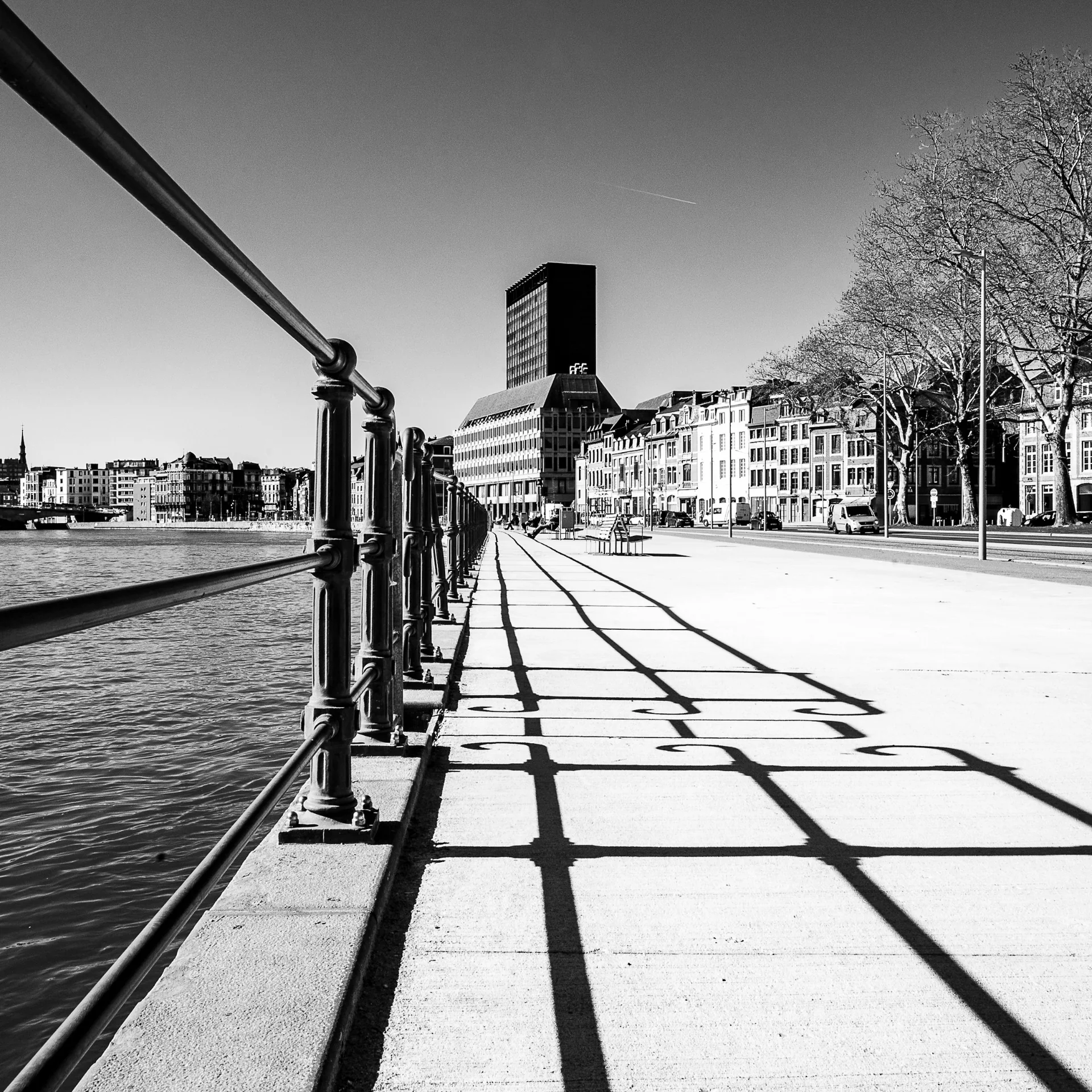 Quai de la Meuse à Liège en noir et blanc, les ombres du garde-corps dessinent un motif sur le trottoir