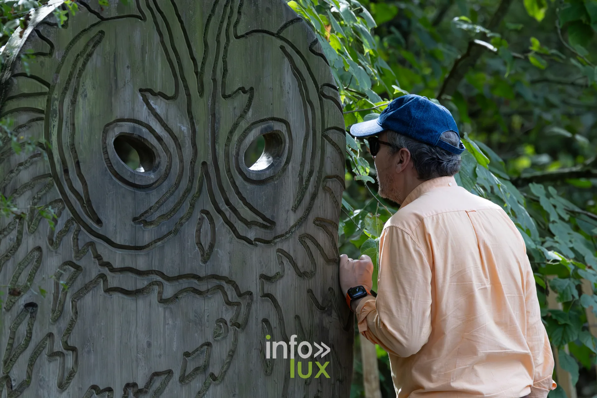 Visiteur pres d'un visage sculpte dans un panneau de bois sur le sentier de l'Aquascope de Virelles